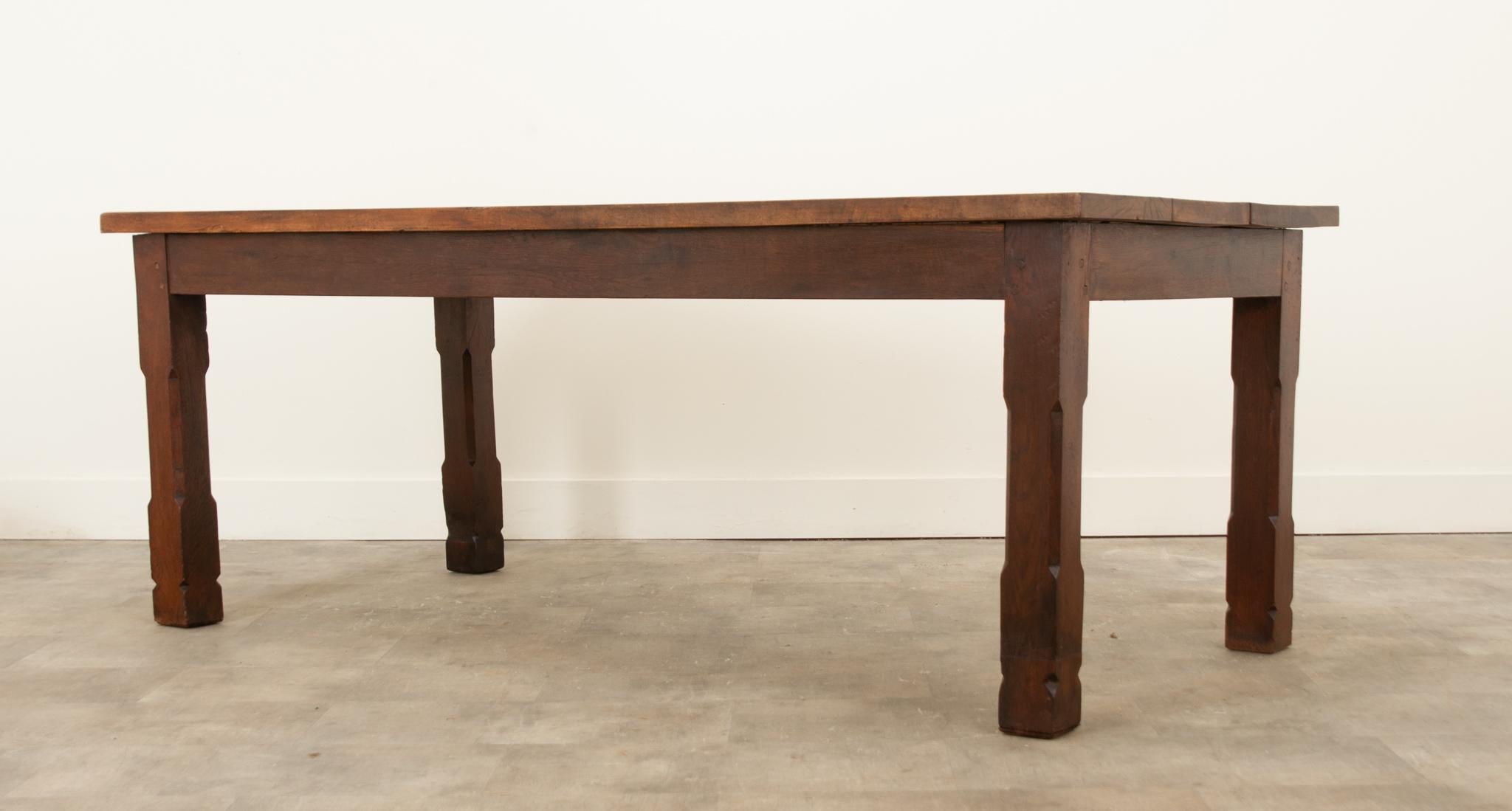 A 19th century French farmhouse table made from oak and walnut. The top is made from three solid oak planks supported on a walnut base, which has a simple apron that follows down to streamlined, well supported,  chamfered and squared legs. This