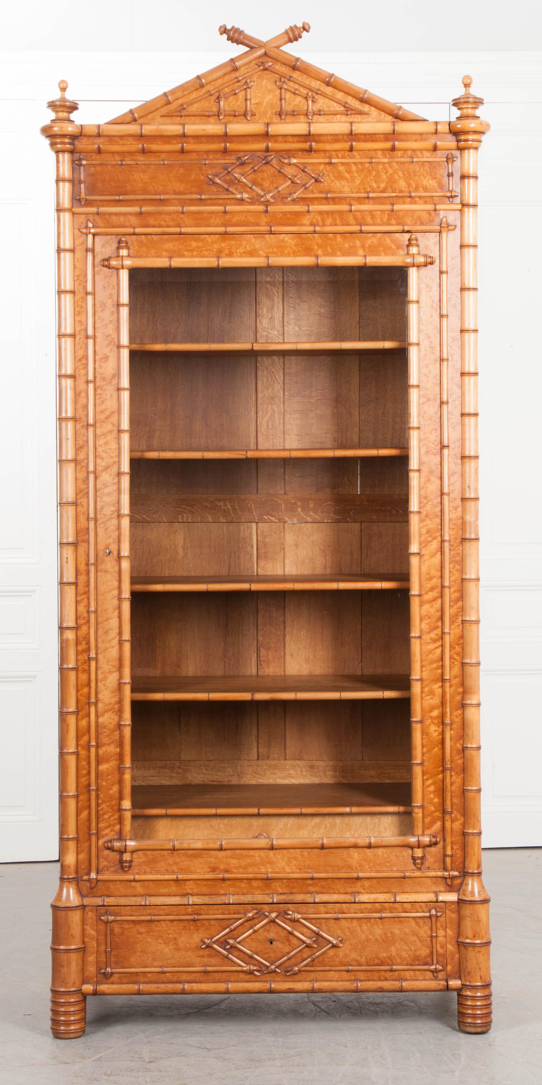 An incredible carved faux bamboo bibliothèque from 1890s France. This single-door bookcase features intricately carved wood, made to look like real bamboo. Exquisite bird’s eye maple complements the blonde toned wood and elevates the excellence of