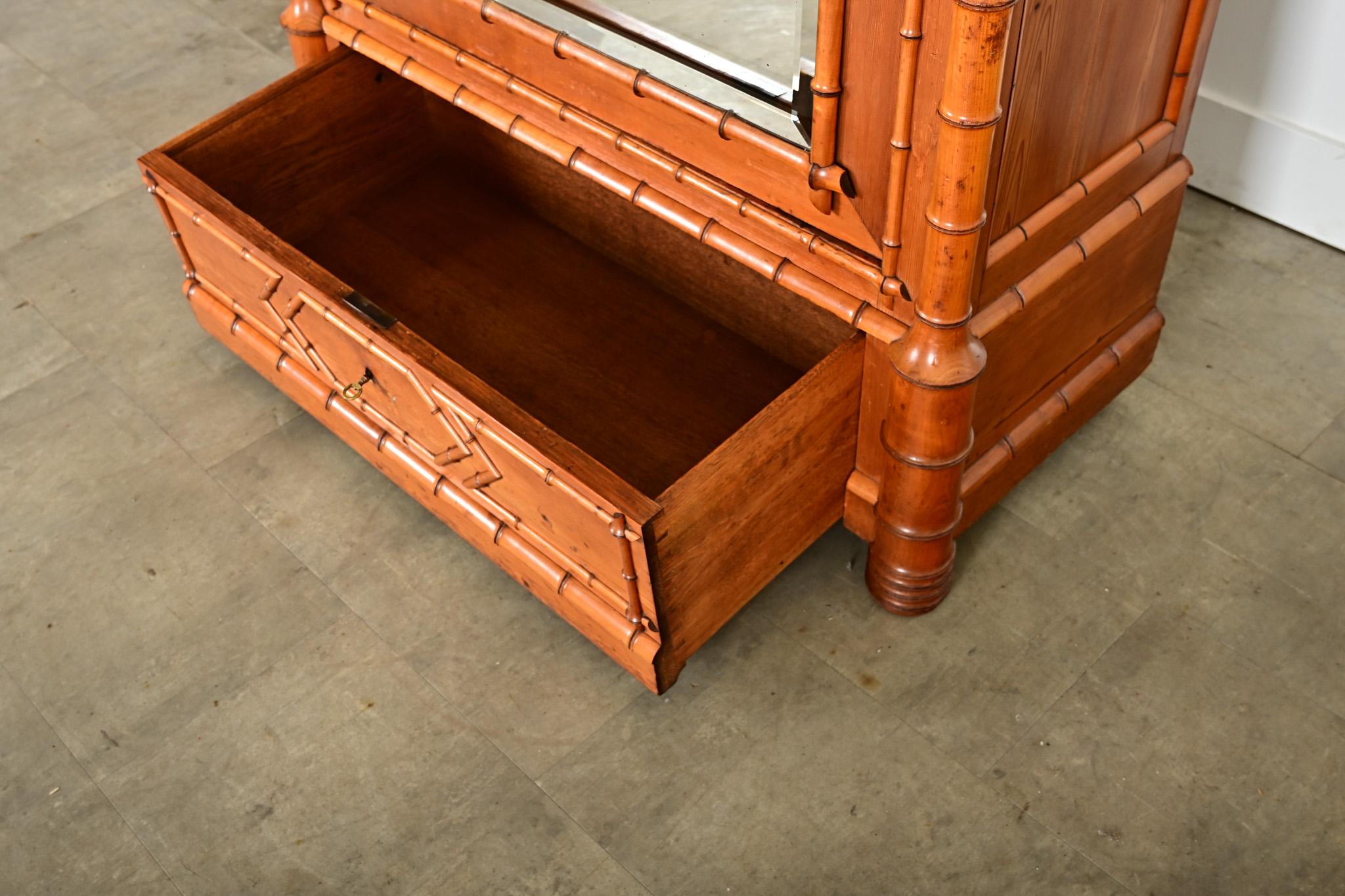 Un armadio in pino finto-bambù proveniente dalla Francia, fine del XIX secolo, con una bella patina ambrata nella cornice. Questo alto mobile contenitore si presenta come una silhouette rettangolare, con una corona a picco sulla sommità e un