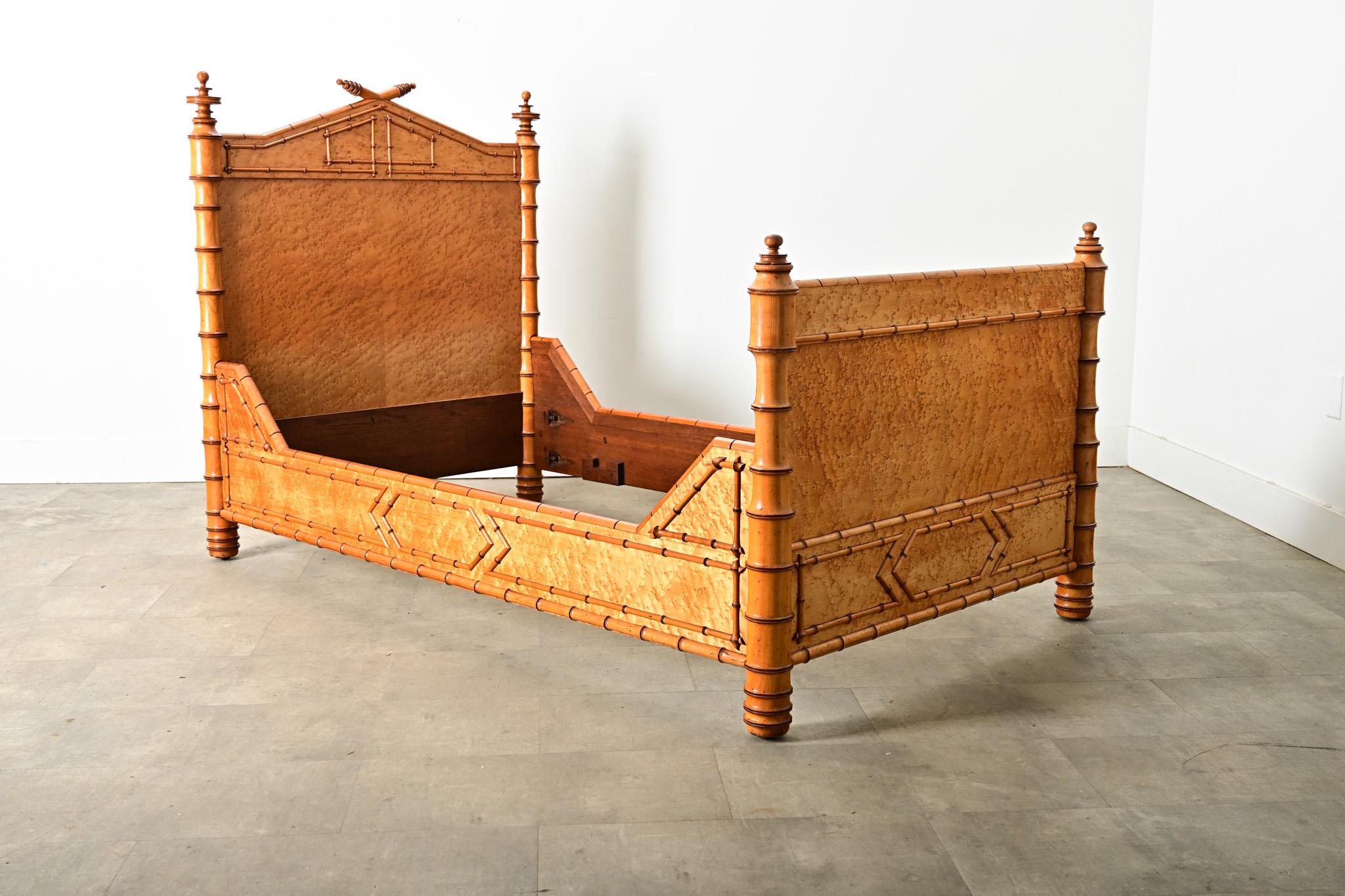 French late 19th century faux bamboo pine and bird’s eye maple bed, reflecting the Aesthetic Movement artistry for organic forms in stylized, decorative ways. The headboard projects ringed finials on the sides and above the pediment at center where
