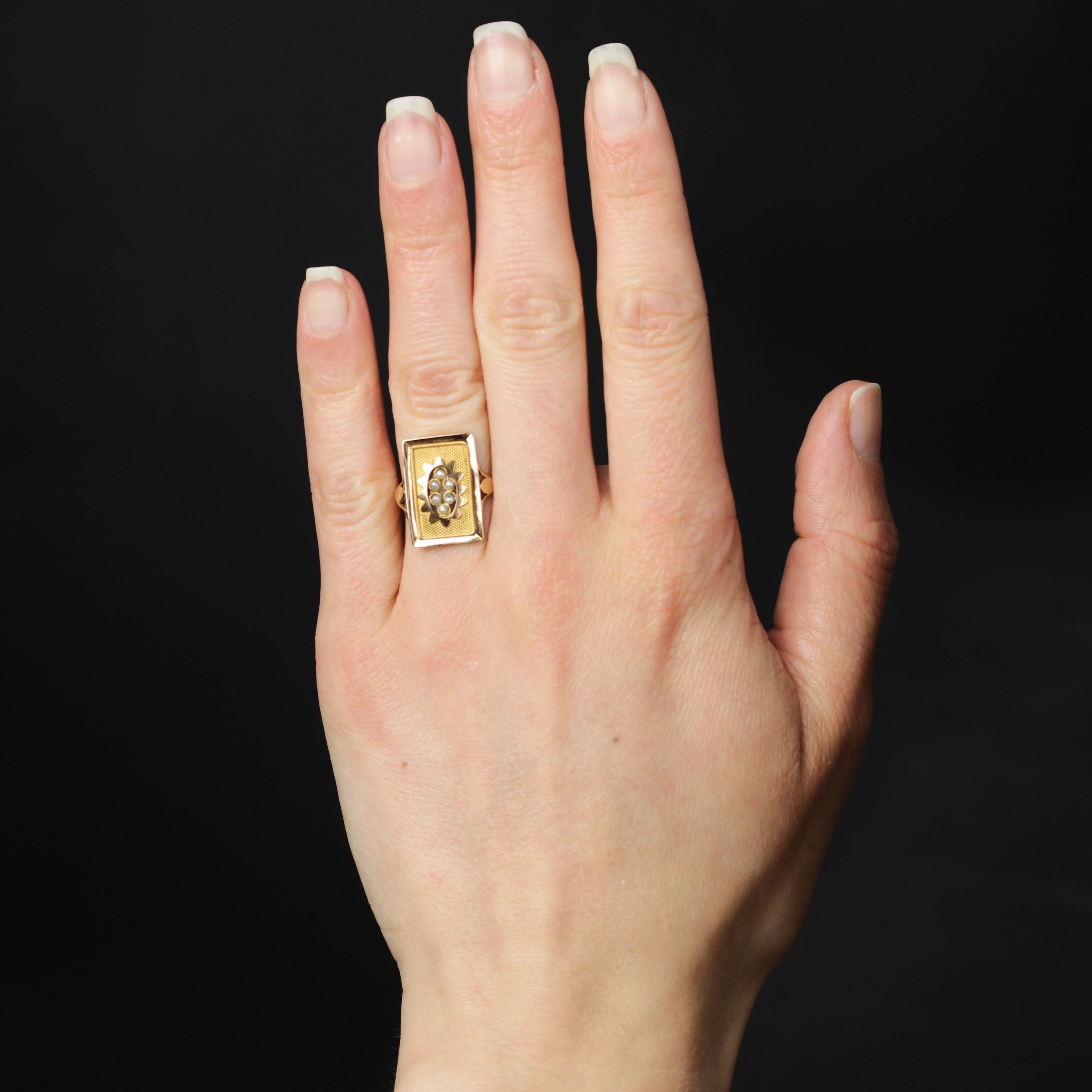 Ring in 18 karat yellow gold, eagle head hallmark.
This original antique ring features a rectangular gold plate with fine pearls held in place by gold wire in the center of a flower motif. The bottom is decorated with a honeycomb in gold and edged