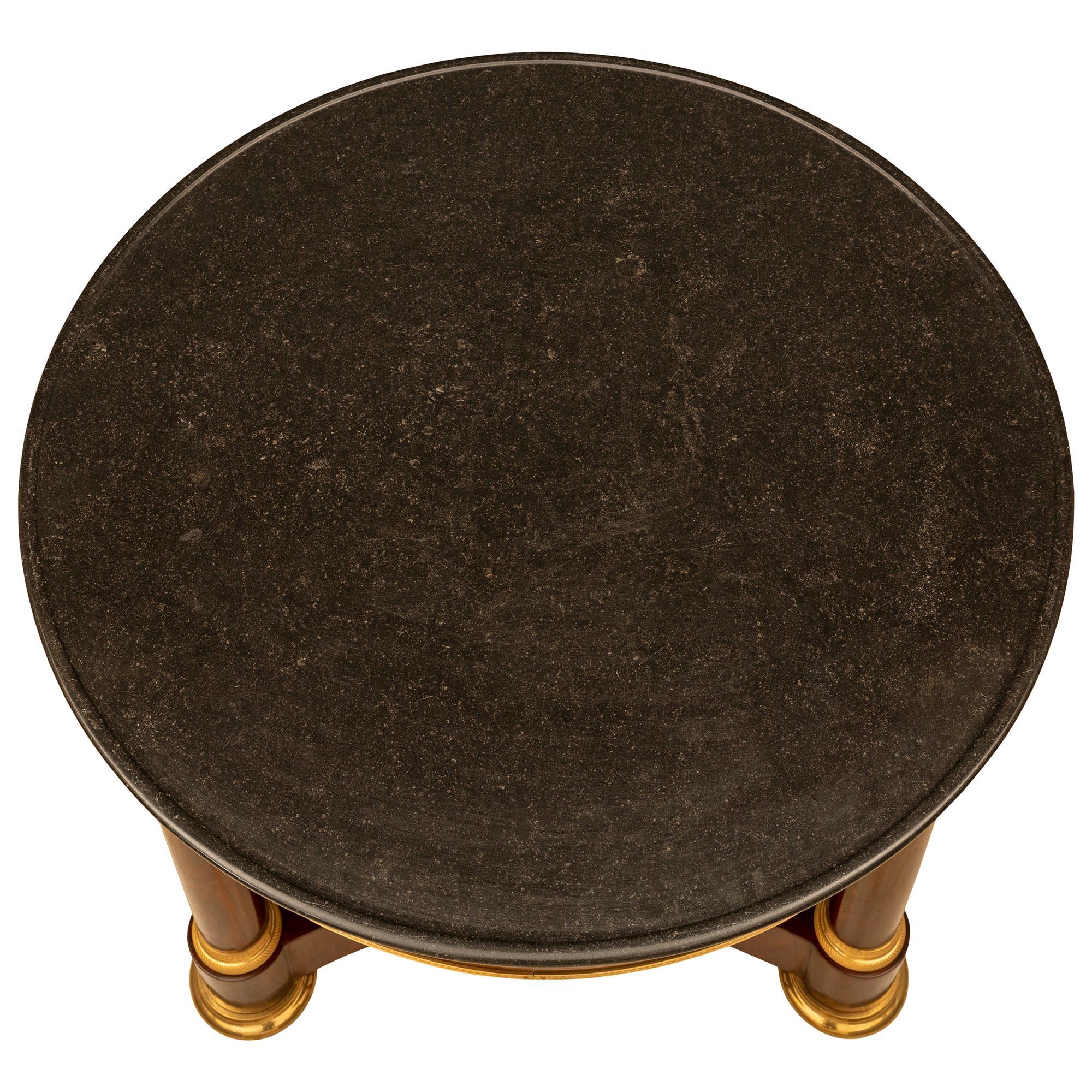 Une très belle table centrale en acajou de style 1er Empire du 19ème siècle. La table repose sur des pieds circulaires en bronze doré, avec roulettes cachées, sous un châssis triangulaire à côtés concaves. Au-dessus se trouvent trois colonnes en
