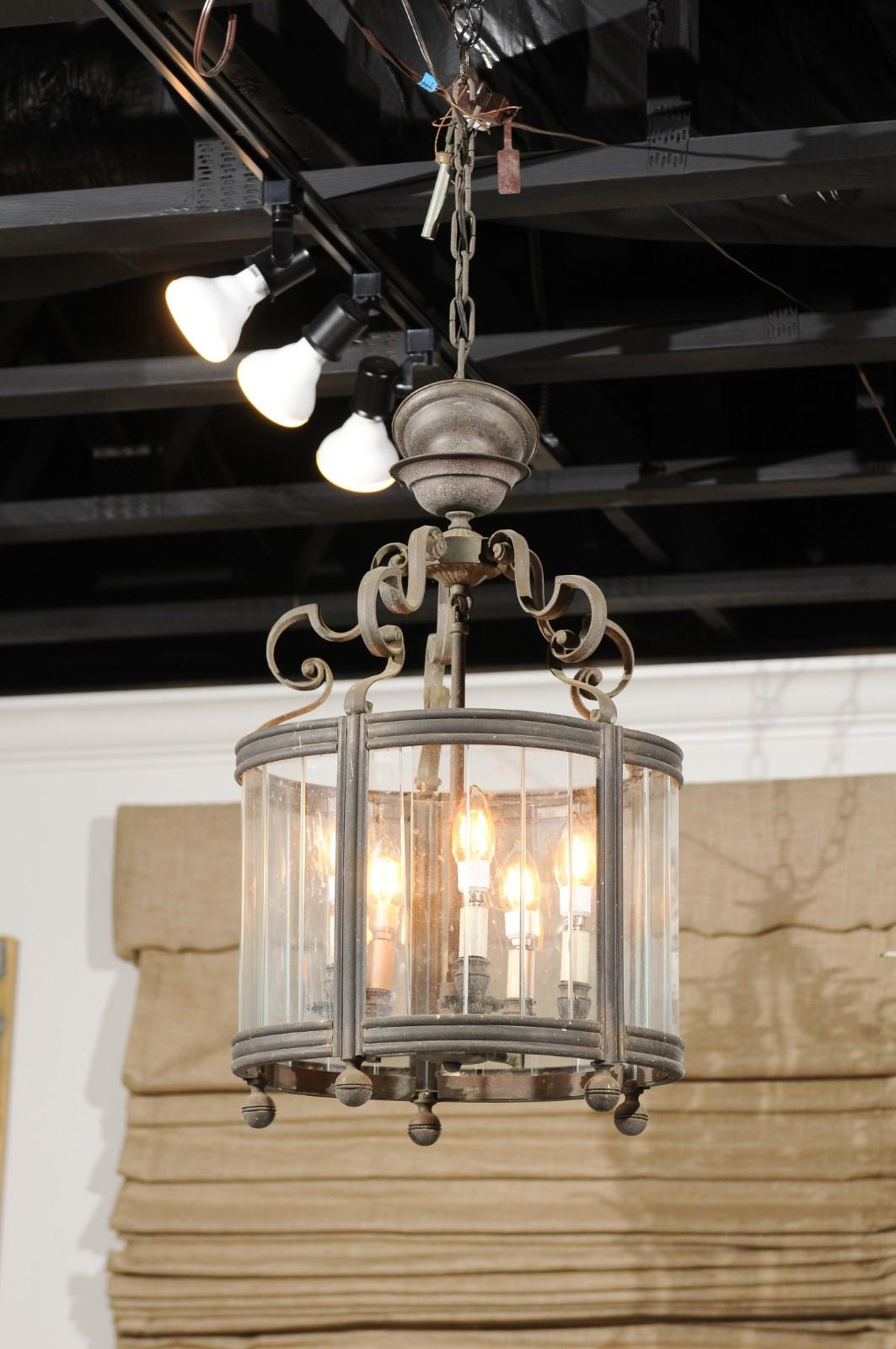 A French five-light iron lantern from the 19th century, with glass panels, scrolling accents and petite spheres. Born in France during the 19th century, this iron lantern features an iron structure topped with scrolling motifs connected to a central