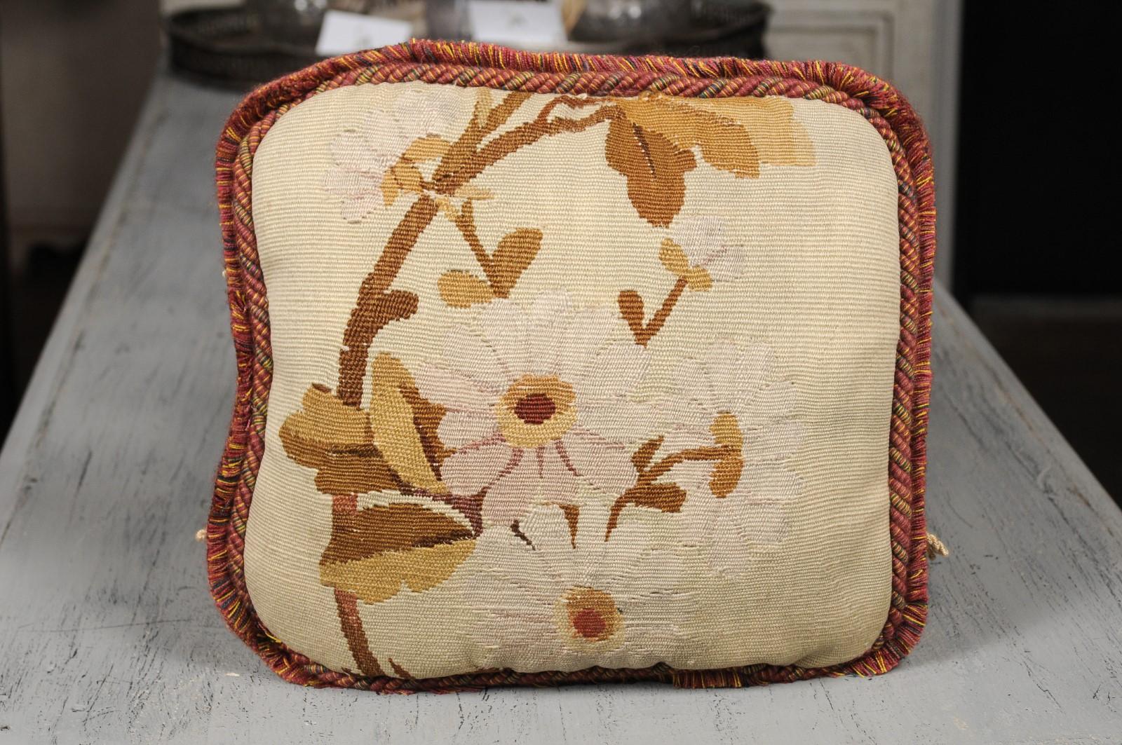 A French Aubusson tapestry pillow from the 19th century, with white daisies, cord trim and fringe accents. Born in central France during the 19th century, this charming rectangular pillow features a floral décor, depicting white daisies and brown