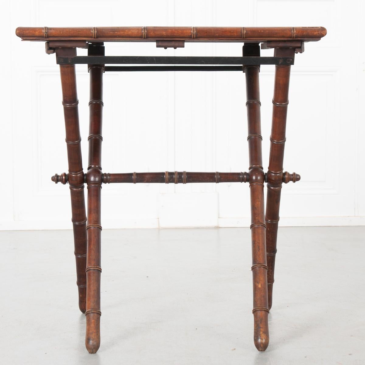 This is a French 19th century faux bamboo table. The top is a light wood surrounded by faux bamboo trim. The legs connected by a stretcher are a darker wood made to resemble bamboo. They will slide in one direction so the top folds down and can be