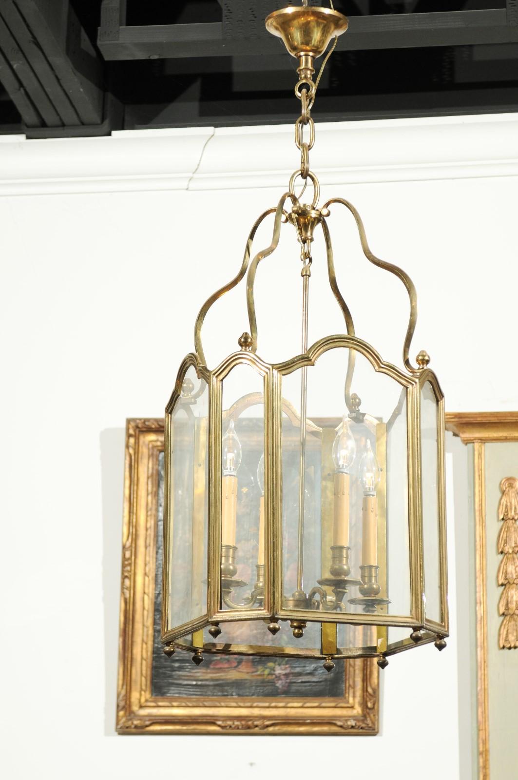A French four-light brass lantern from the 19th century with glass panels and scrolling armature. Born in France during the 19th century, this elegant lantern features a brass armature, with scrolling motifs and molded panels accented with