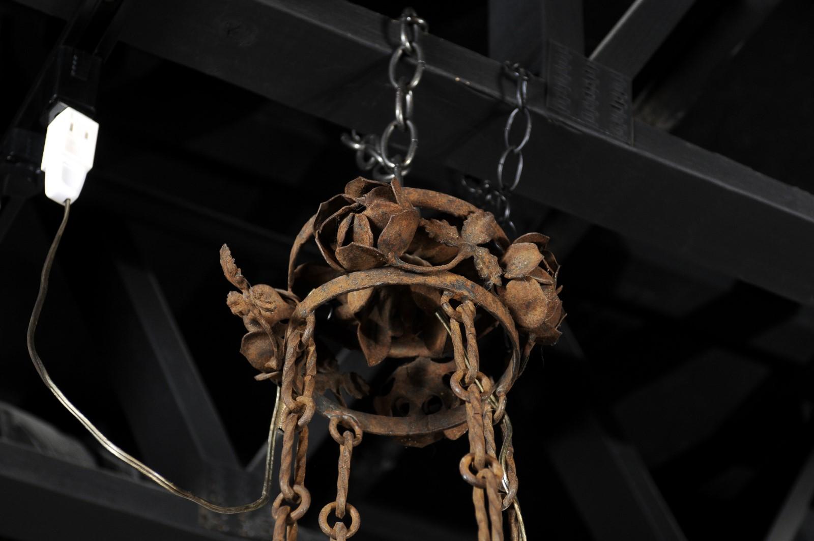 A French four-light iron chandelier from the 19th century, with flowers and vines. Crafted in France during the 19th century, this four-light chandelier features a small canopy adorned with roses, connected to the bottom section through profiled