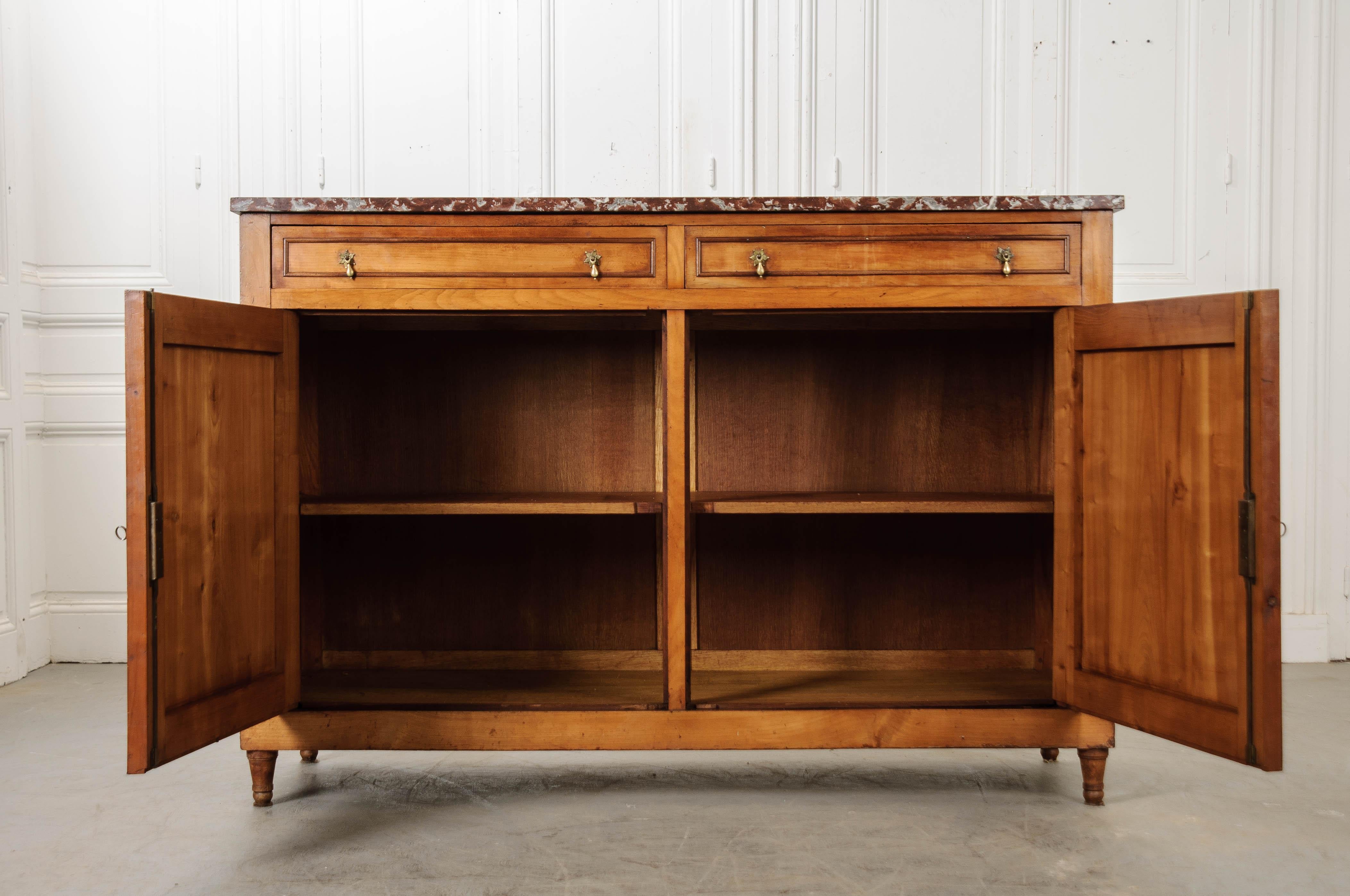 A beautifully-toned fruitwood buffet, made in France, circa 1860. The two-door, two-drawer case piece is topped with an incredibly beautiful piece of rouge and gray marble. With the exception of an old break at the piece’s back corner, the marble is