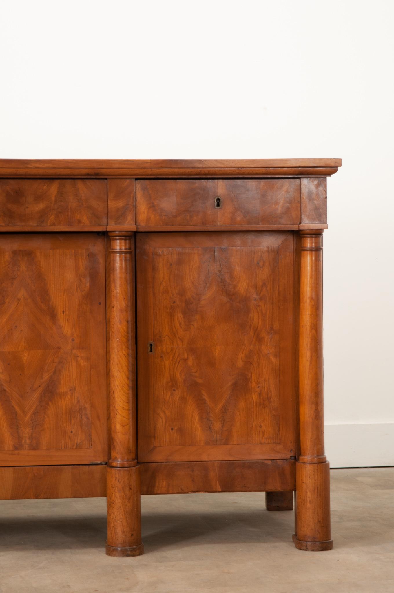 Dazzling bookmatched veneer and figured fruitwood make this 19th century French Empire style enfilade truly stunning. Hand-crafted in France circa 1850, this enfilade features a gorgeous, smooth, well patinated top with a deep molded edge which sits
