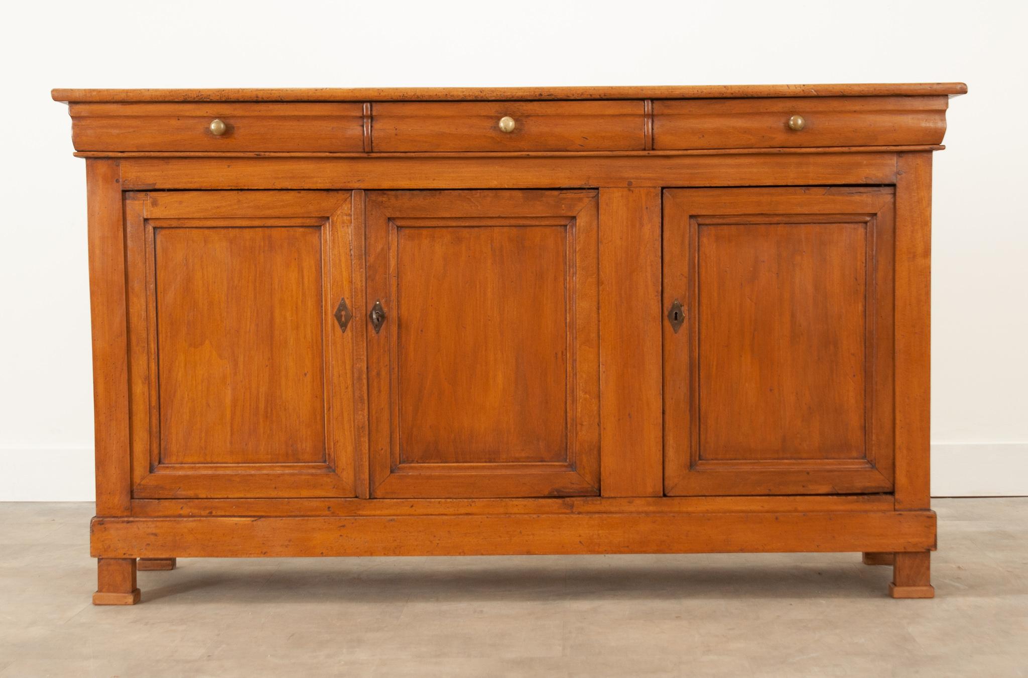 A fantastic fruitwood enfilade from 19th century France. The beautiful solid wood case antique has a linear composition with subtle curved details, indicative of the Louis Philippe style. Three shaped-front drawers are housed within the apron and