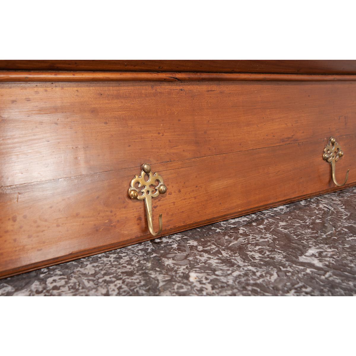 A charming French hat or coat rack, with a shelf. Six hooks are situated along a horizontal bar located under the shelf. The aged finish and uniquely shaped bracket supports give the piece a welcoming charm. This piece has so many possibilities,