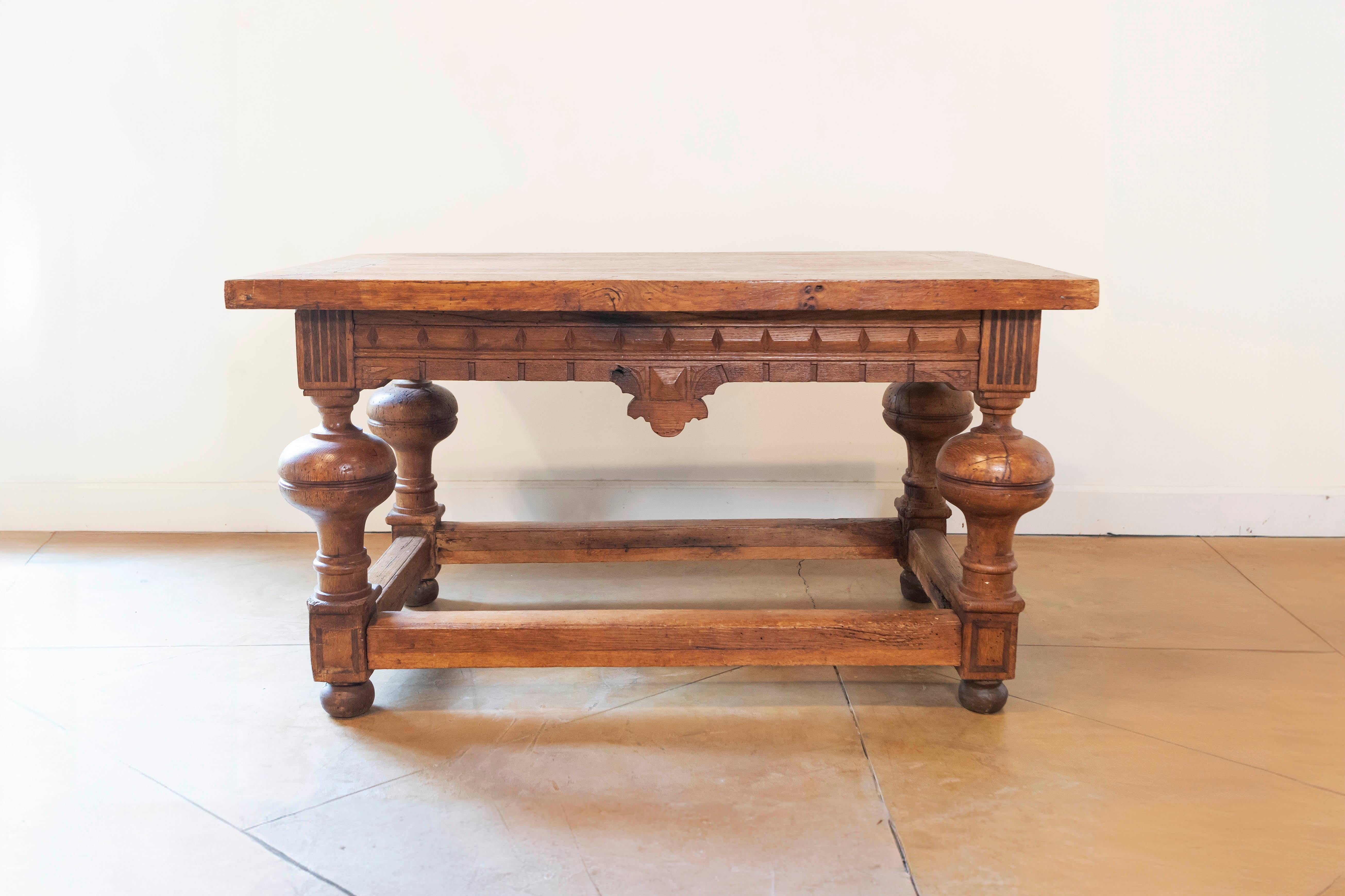 A French fruitwood table from the 19th century, with planked top, carved apron and bulbous legs. Created in France during the 19th century, this table features a rectangular planked top sitting above an eye-catching apron, adorned in its center with