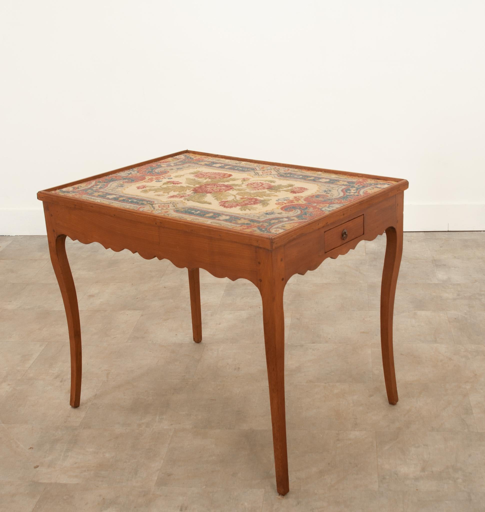 This unique little table is a great way to add color and texture to your space. Crafted in France during the 19th century from solid fruitwood with a needlepoint tapestry top. The textile top is in wonderful antique condition and is a lovely display