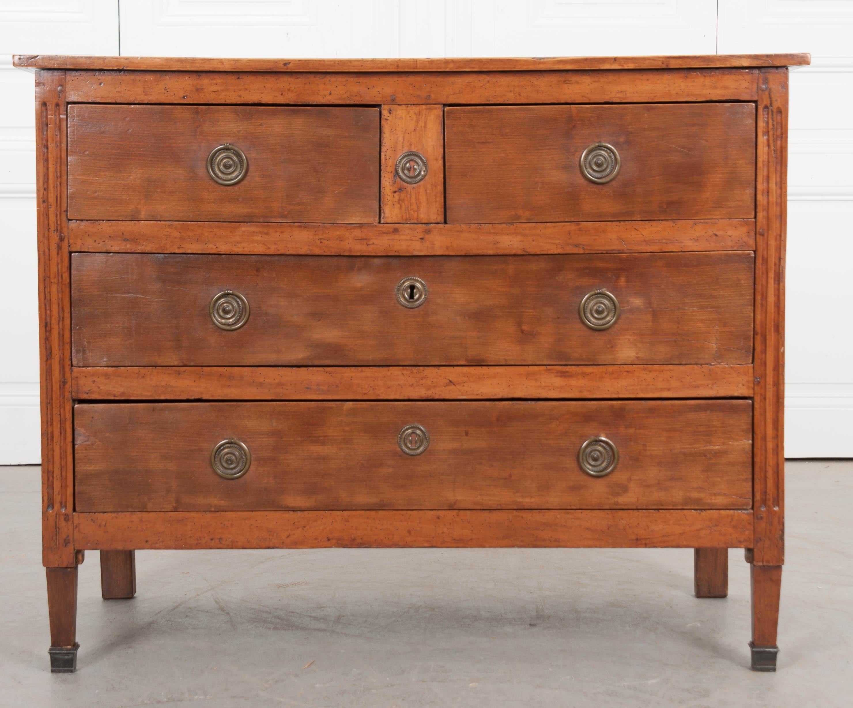 This attractively restrained French Directoire-style four-drawer commode, features two short drawers over two long drawers, and fitted with patinated-brass ring handles and escutcheons.