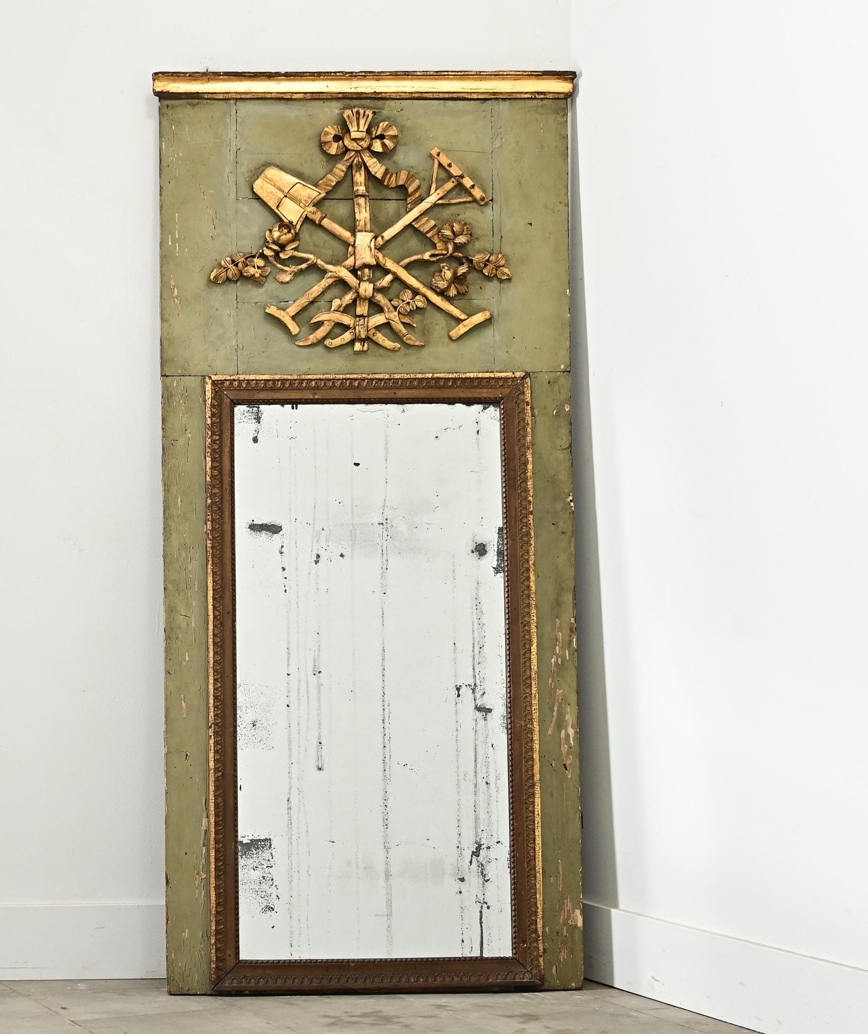 Un miroir trumeau unique et personnel du XIXe siècle en France, présentant un assortiment d'outils de jardinier sculptés et dorés dans le panneau au-dessus de la vitre. Cet amalgame enchevêtré se compose d'un ruban noué, au-dessus d'une pelle et