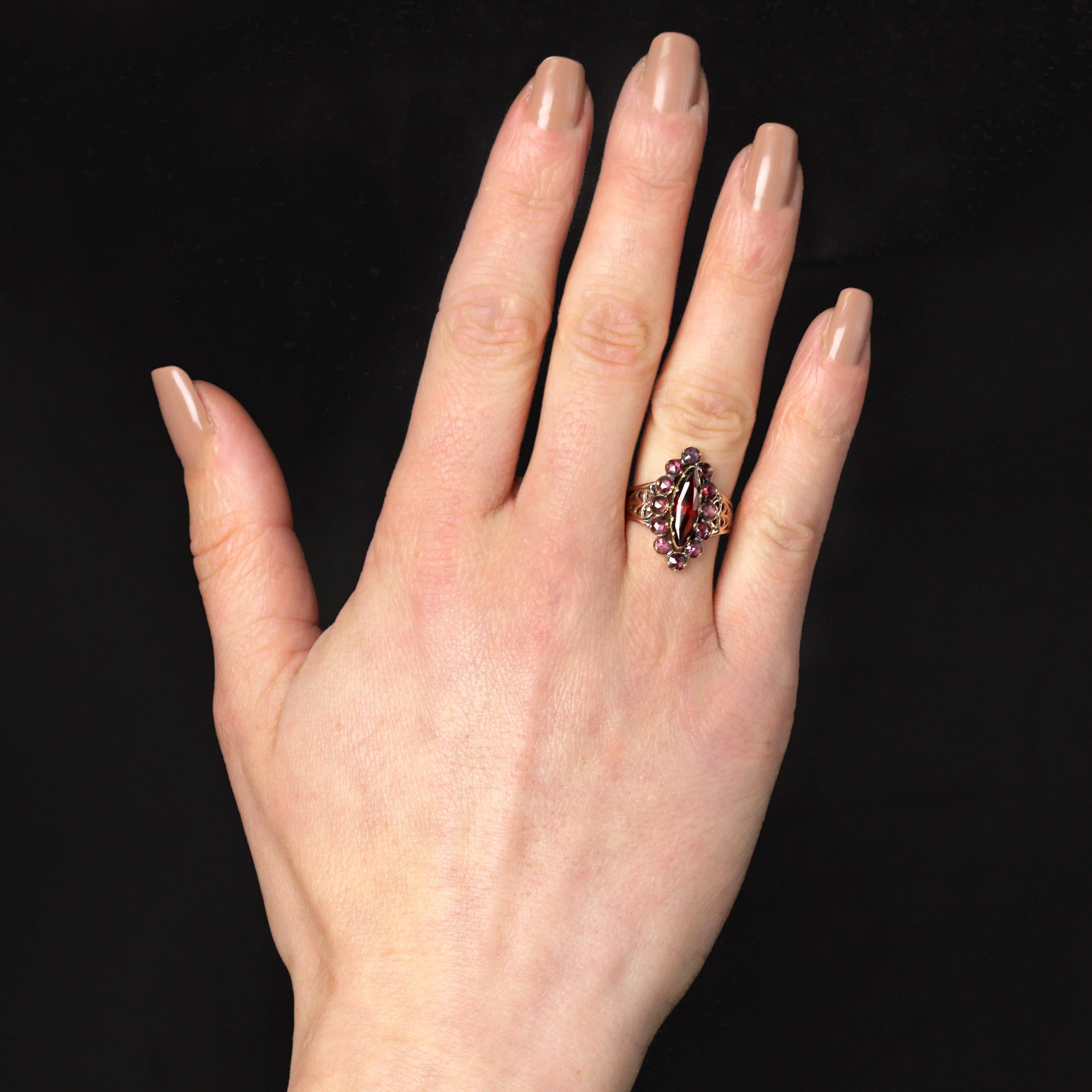 Bague en or rose 18 carats, poinçon tête de cheval.
Cette bague marquise antique féminine est sertie de grenats ronds taillés en rose pourpre et d'un grenat rouge intense taillé en navette au centre. De chaque côté de la tête, le début de l'anneau
