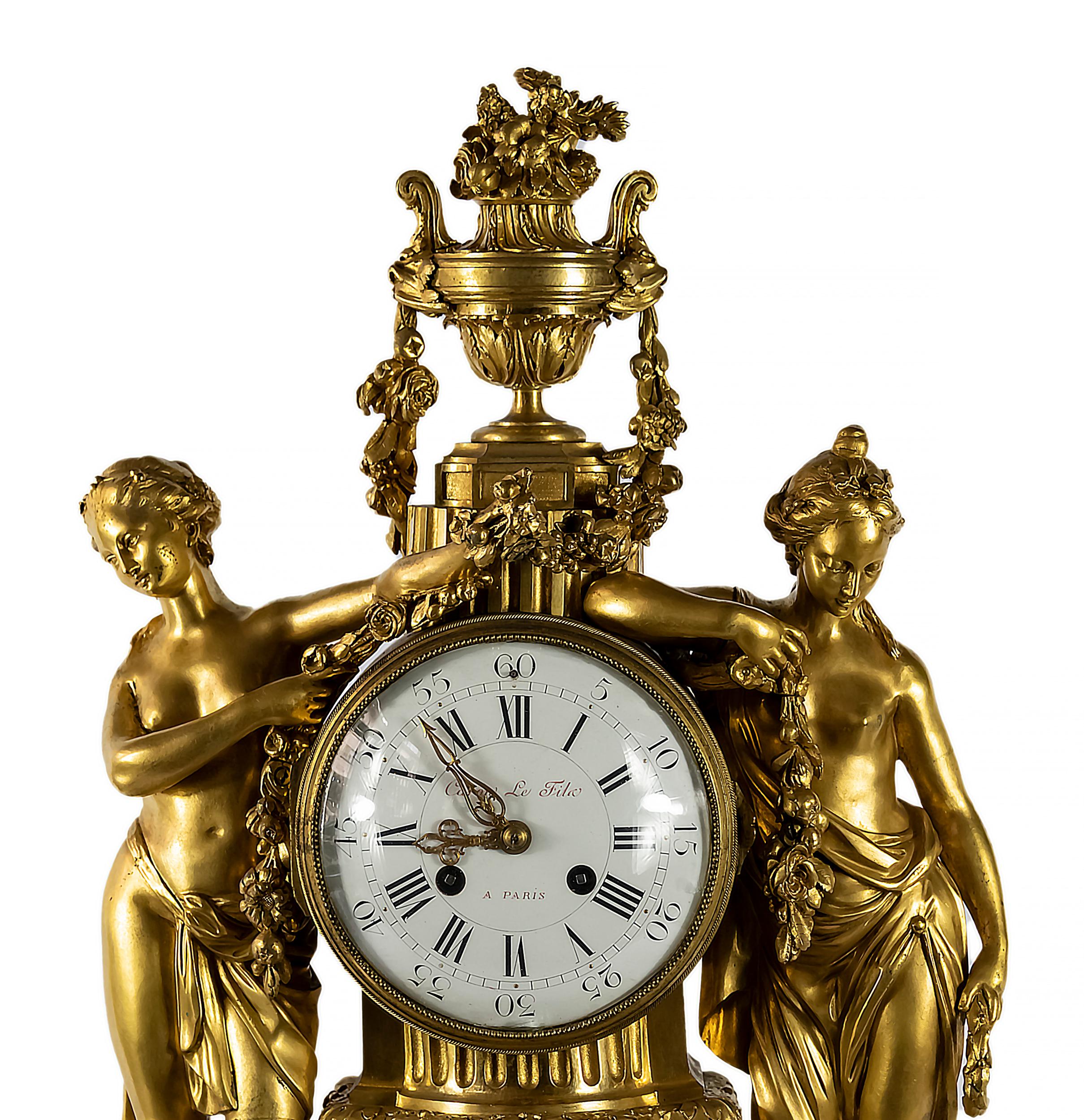 Antique 19th century French gilded bronze and white marble mantel clock. 
The clock is decorated with beautiful female figures holding floral garlands and vase with flowers on the top. 
White enamel dial plaque is marked Caron Le Fils A Paris and