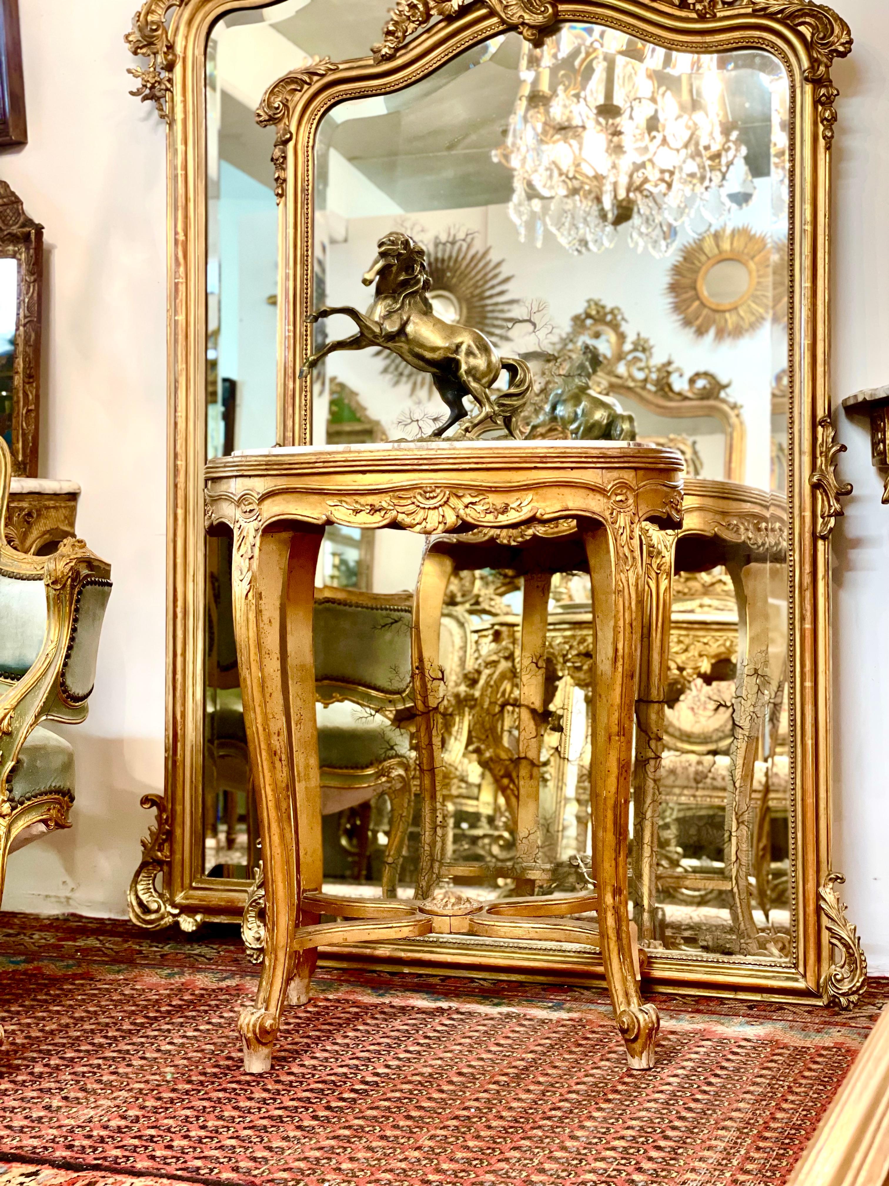 Très charmante table de centre en bois doré d'époque Napoléon III, de forme ovale, avec plateau en marbre. Cette table ornée repose sur quatre pieds cabriole galbés reliés par une entretoise en forme de X et se terminant par des pieds à volutes. La