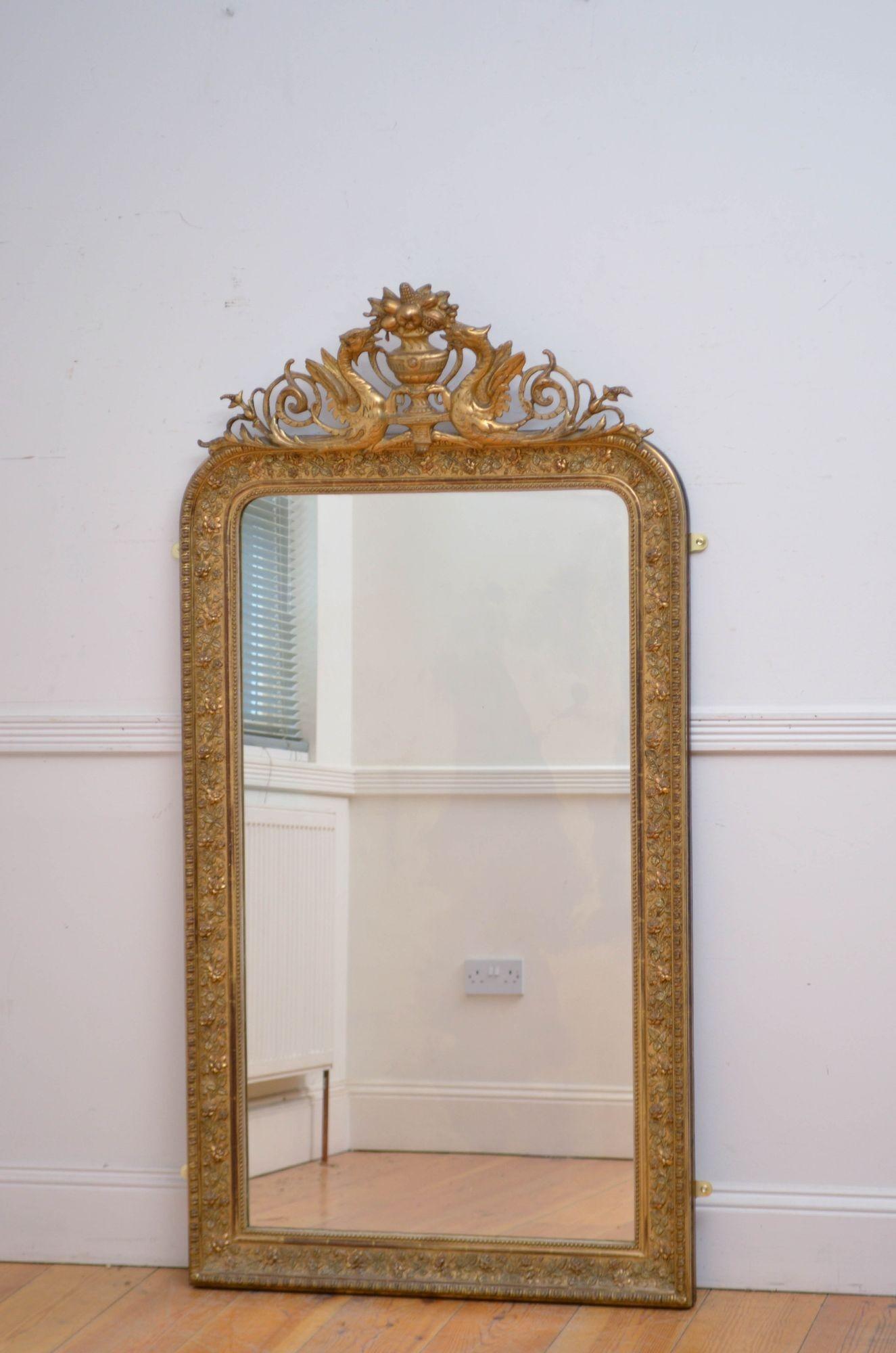 Sn5563 Eccezionale specchio da parete francese in legno dorato, con vetro originale leggermente sfuocato e cornice concava dorata con ampie decorazioni floreali e uno stemma a forma di vaso affiancato da draghi e sottili volute di fogliame. Questo