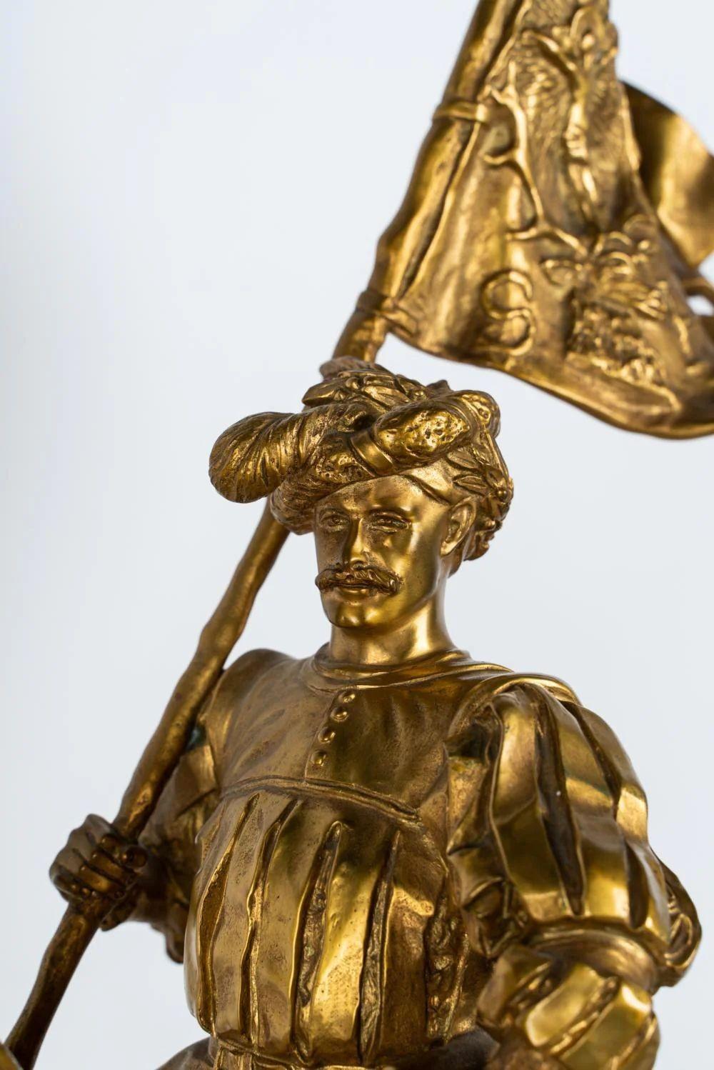 Una tradizionale scultura in bronzo dorato di Emmanuel Frémiet su una base di marmo, che ritrae Sant'Uberto a cavallo mentre mostra una bandiera raffigurante Gesù crocifisso, simbolo della sua conversione e del suo impegno nei suoi confronti.