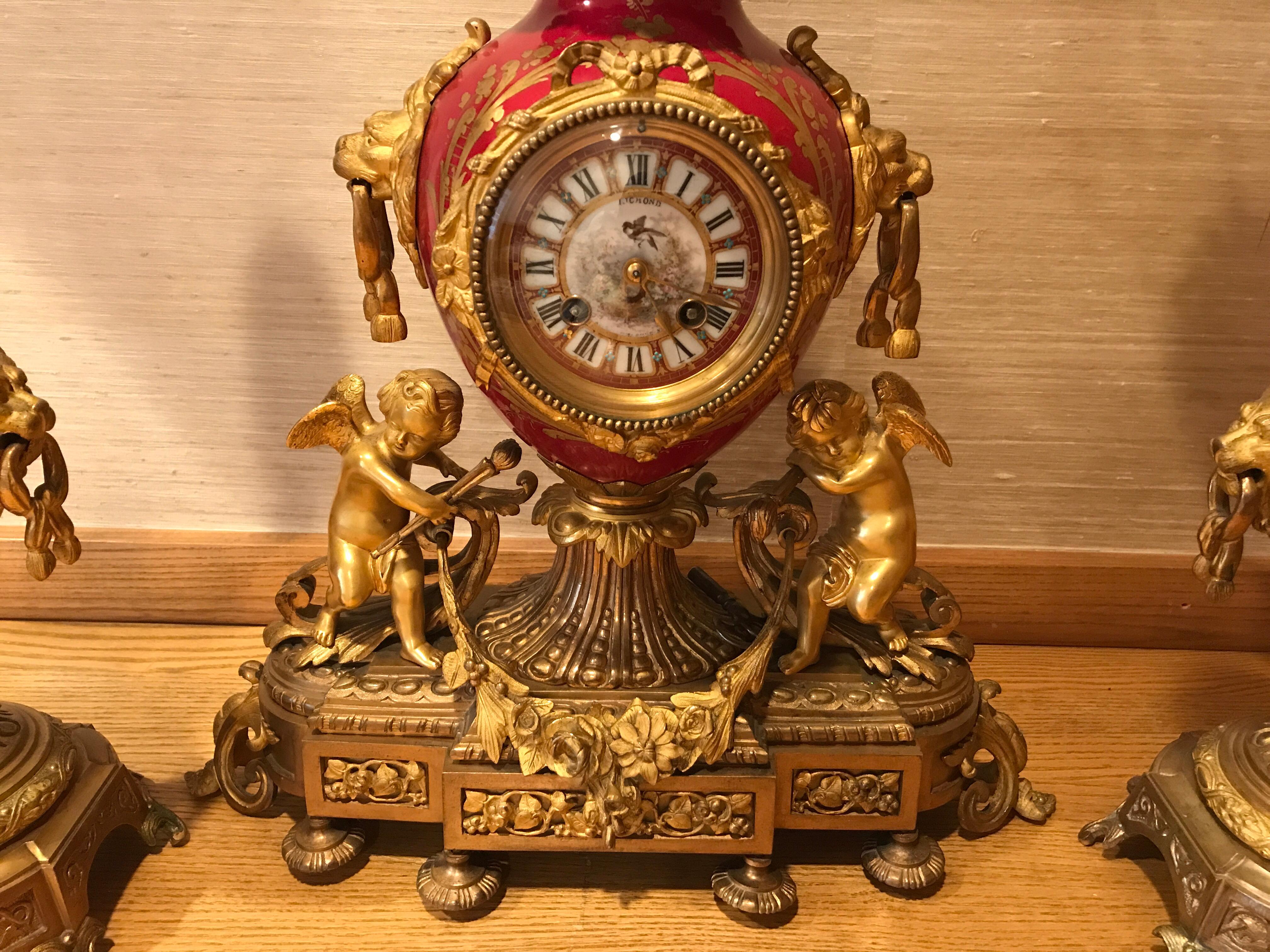 Beautiful 19th century gilt bronze mounted porcelain and enamel garniture set. Details include putti’s and lions clock clock face reads Richond  on top. No.11 on bottom
Candelabras are 21.5 H x 11 W x 10 D.