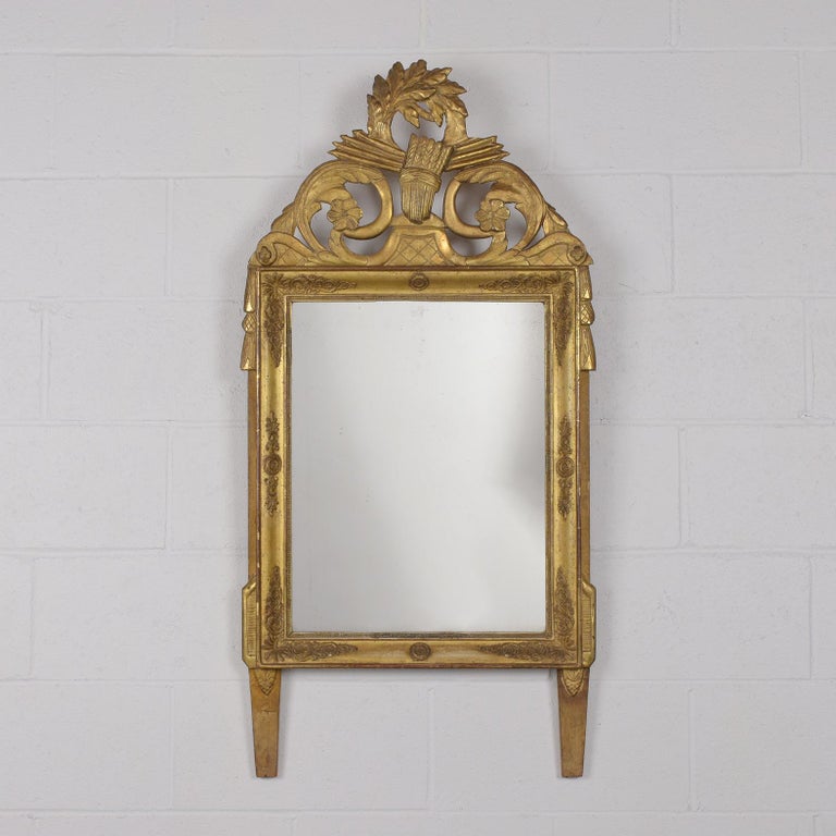 This early 19th-century French wall mirror has beautiful hand-carved details on the crest and throughout the frame. This mirror frame still has its original water gilt finish and a clear mirror in a good condition and is fully reflective.