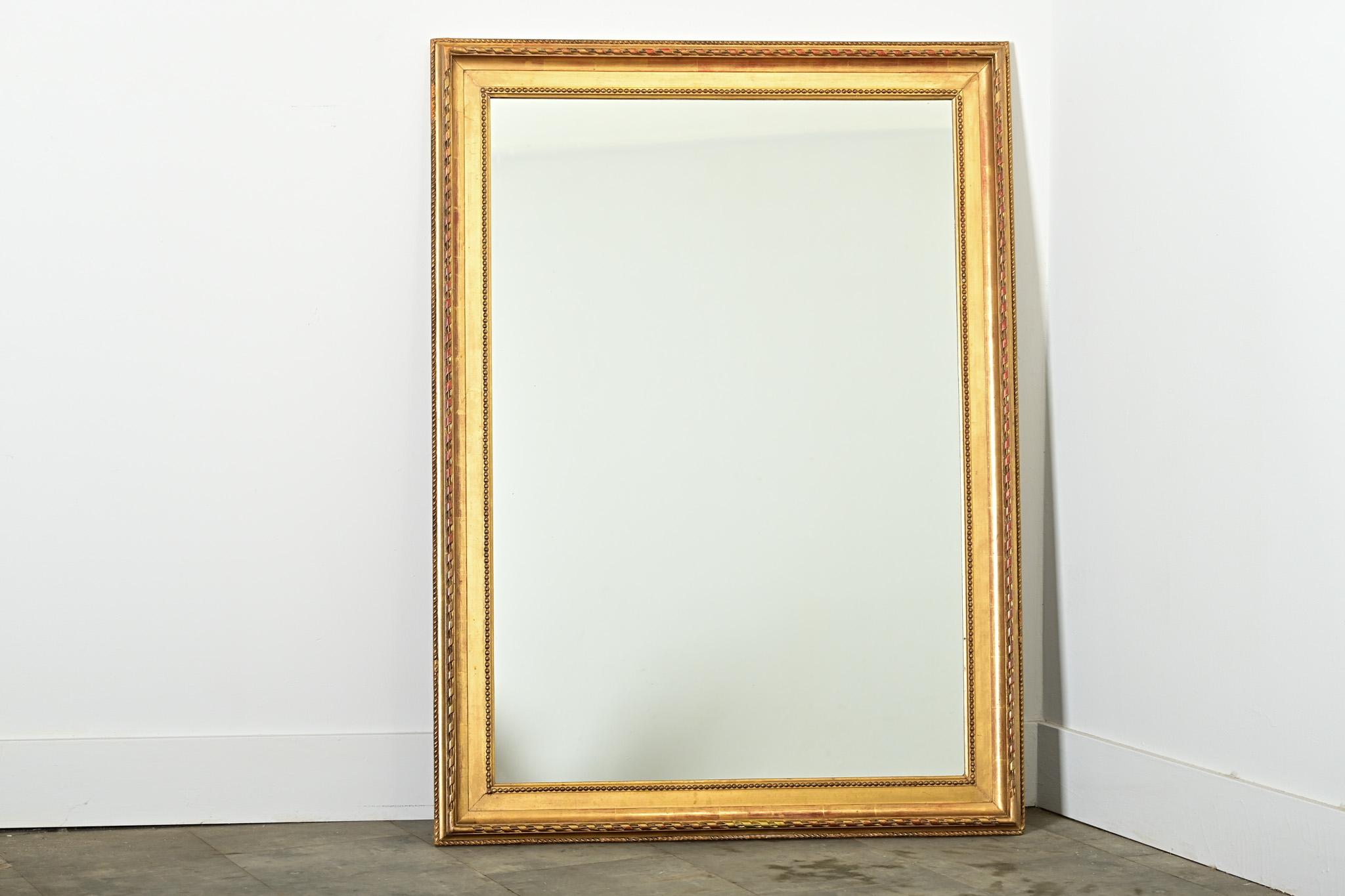 Superbe miroir mural français du XIXe siècle, doré à l'or fin, avec des motifs classiques dans la moulure, allant d'un bord godronné à un ruban torsadé, en passant par une texture perlée, créant un fort intérêt visuel autour du cadre rectangulaire.