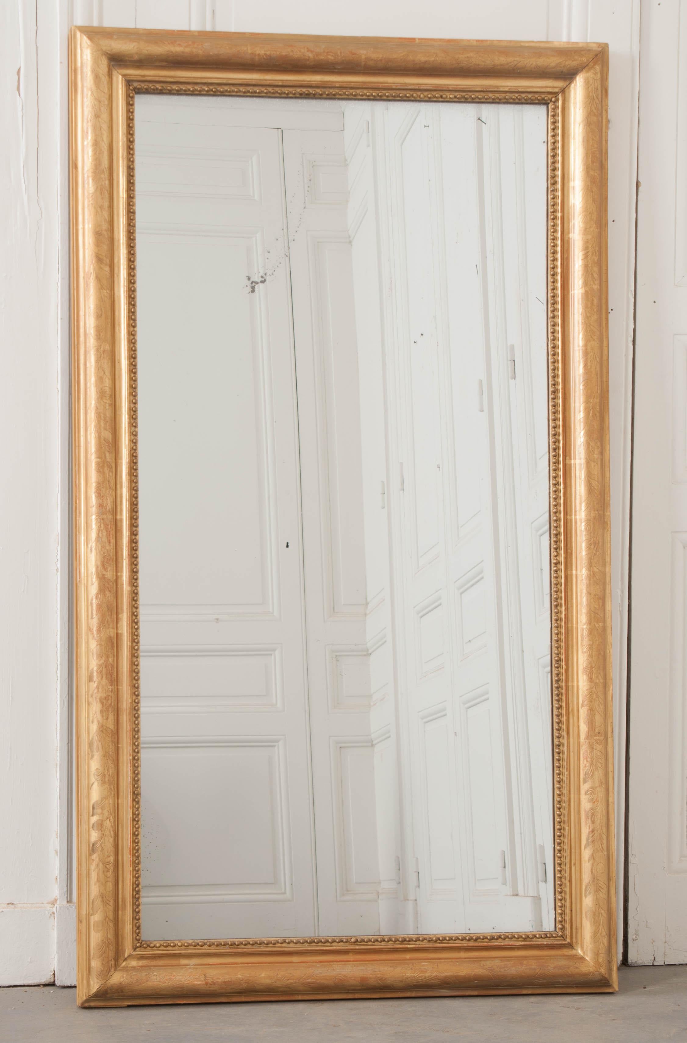 Simple flower motif is etched on all sides of this gold gilt, symmetrical mirror. The frame surrounds its original mirror glass which has light foxing and crystallization throughout, circa 1820s.