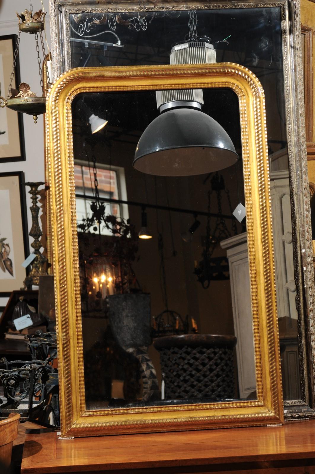 A French Louis-Philippe giltwood mirror from the 19th century, with ribbed frame. Born in France during the politically ever-changing 19th century, this exquisite mirror features the traditional silhouette of the Louis-Philippe period. Simple yet