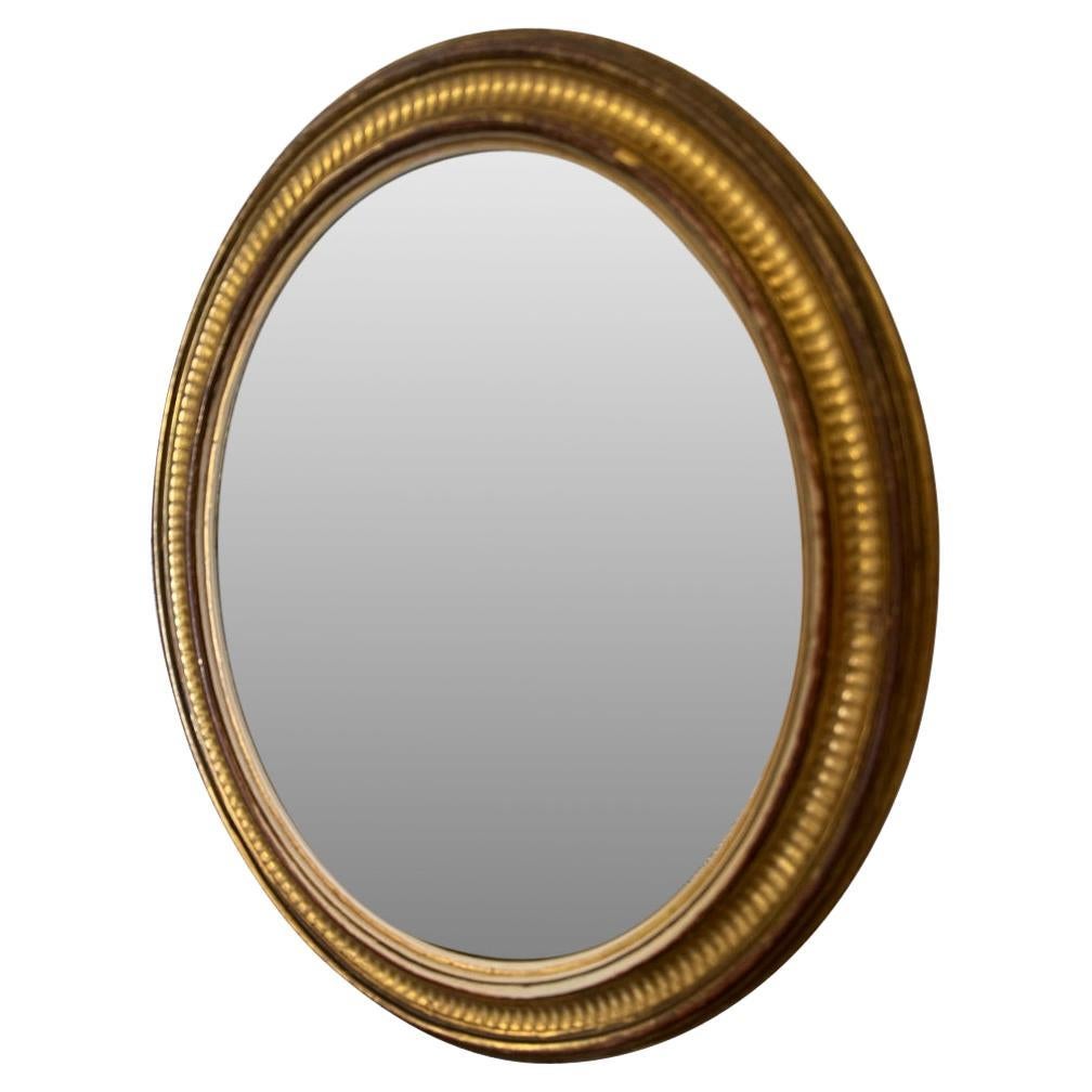 Uno specchio francese di forma ovale in legno dorato, molto bello e di dimensioni ridotte. Bella patina. 
