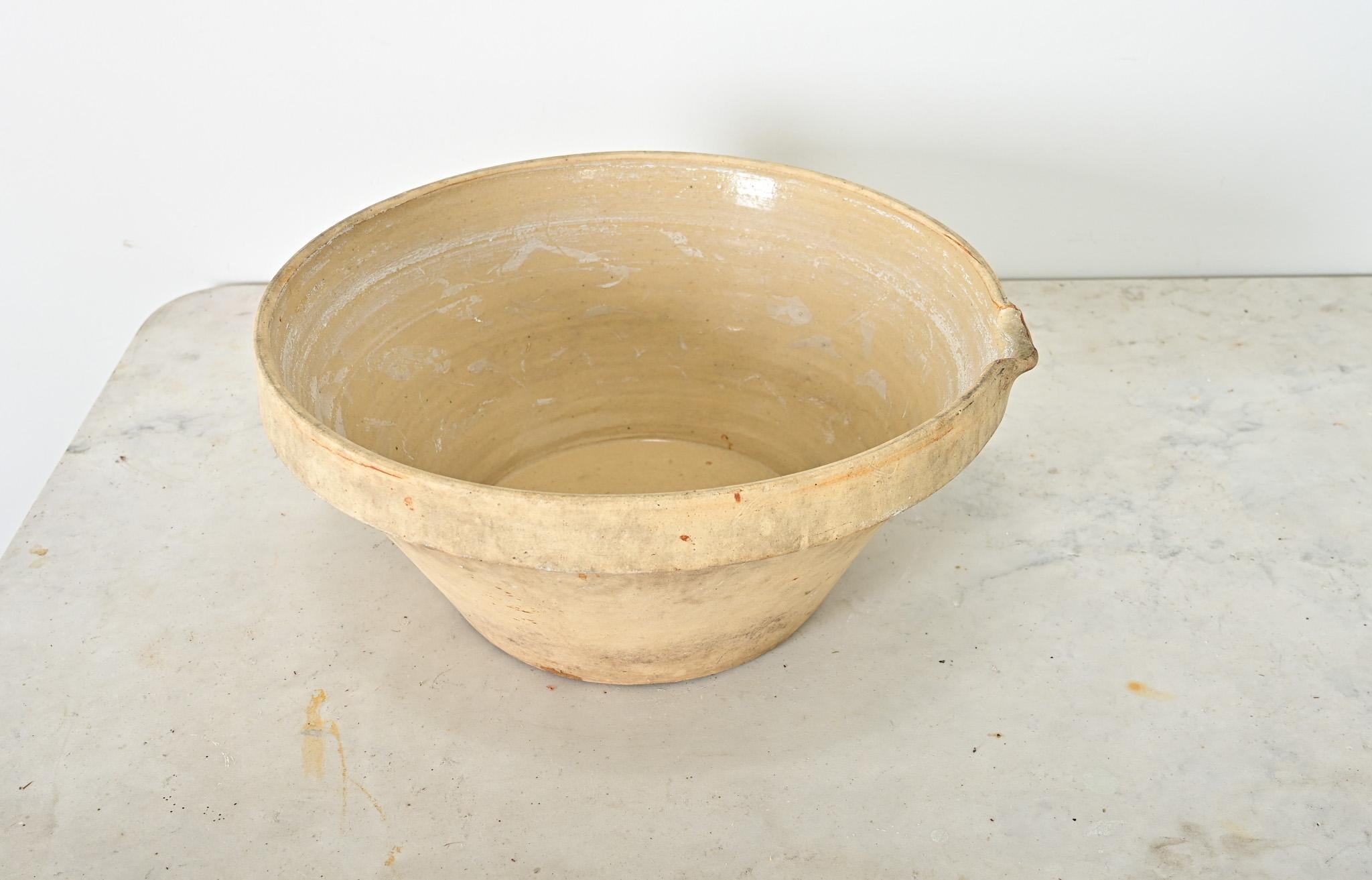 A lovely glazed terra cotta cream bowl from 19th century France. This earthen bowl, also known as a pancheon, was used to stand milk while the cream separates. The cream is then poured off the top with the small spout found on the pot’s lip. This