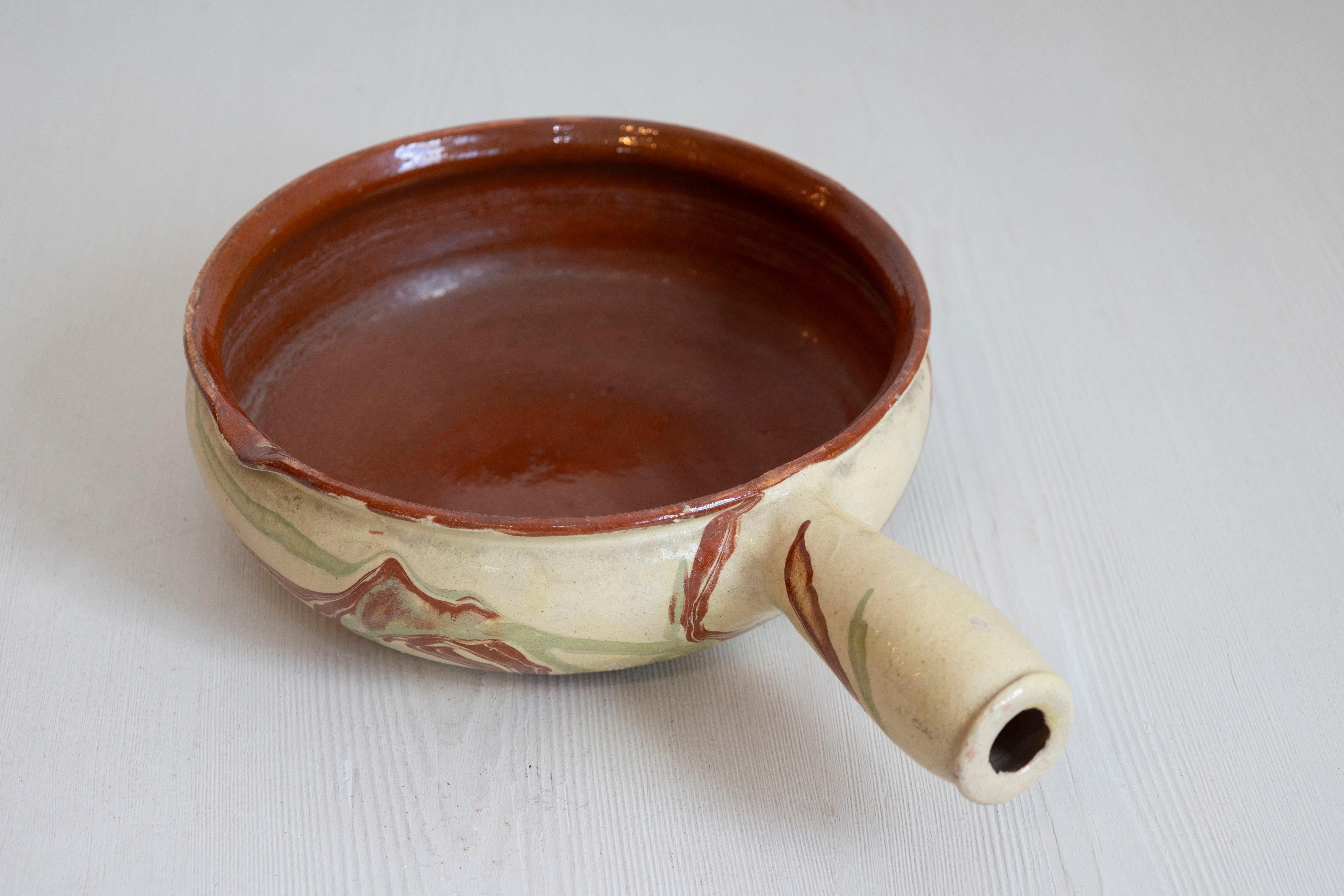 Plat de service en poterie émaillée française du XIXe siècle, avec terre cuite et glaçure dorée. Créé en France au cours du XIXe siècle, ce plat en poterie présente un corps circulaire orné d'une glaçure de couleur terre cuite et verte qui accentue