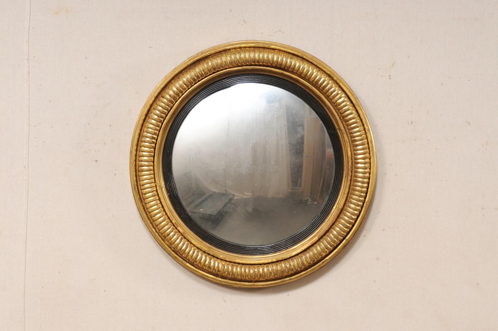 A French carved and gilt wood bullseye mirror from the 19th century. This antique mirror from France is has a round-shaped mirror at center, set within a circular frame with a textured rib trim flanked within outer and inner molding. The inner trim