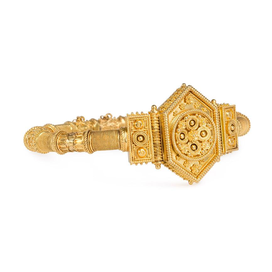 An articulated antique gold bracelet in the Etruscan style with applied wirework and granulation centering on a hexagonal foliate ornament, in 18k. France, original box.  
Dimensions:  Inner circumference 6 1/2