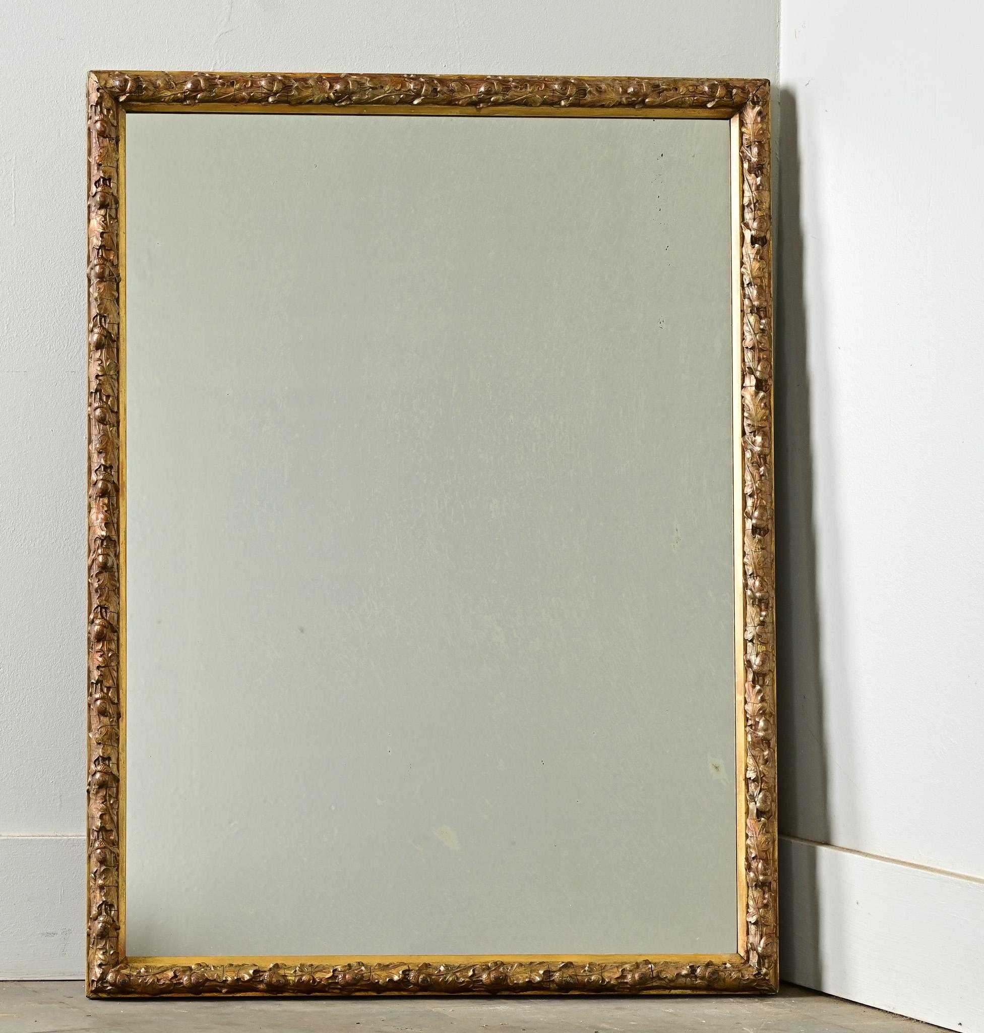 Charming French antique mirror in gold gilt with intricately carved acorns and oak leaves. Minimal foxing in the original mirror plate; a lovely size to hang where this unique piece can be used and appreciated. The frame is symmetrical to hang in