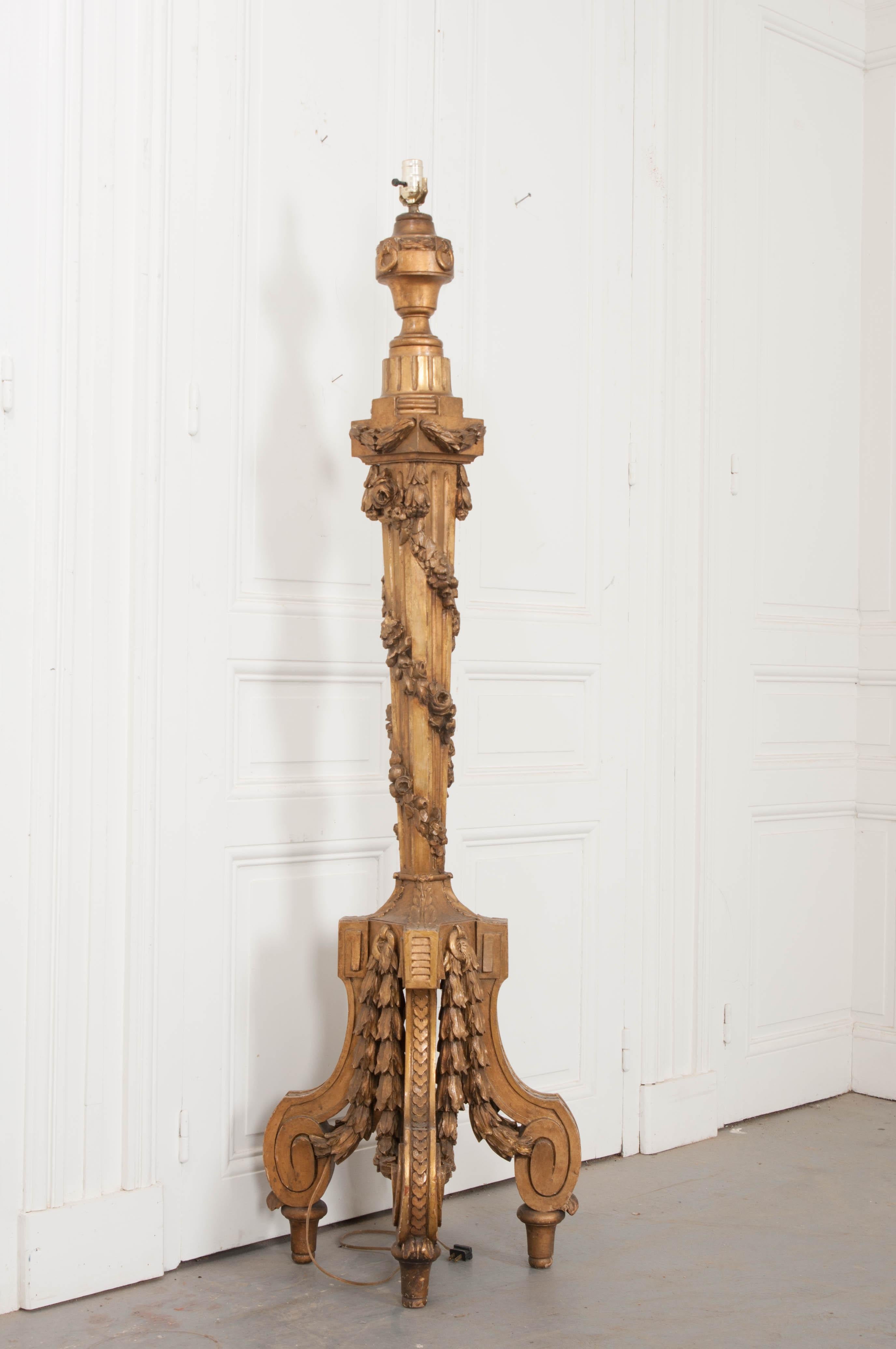 This beautifully carved candlestick is from the middle 1800s, once used in a church, it has been converted to a floor lamp. The top has carved gold gilt garlands the swag horizontally around the column’s capital. More carved garlands twist down the