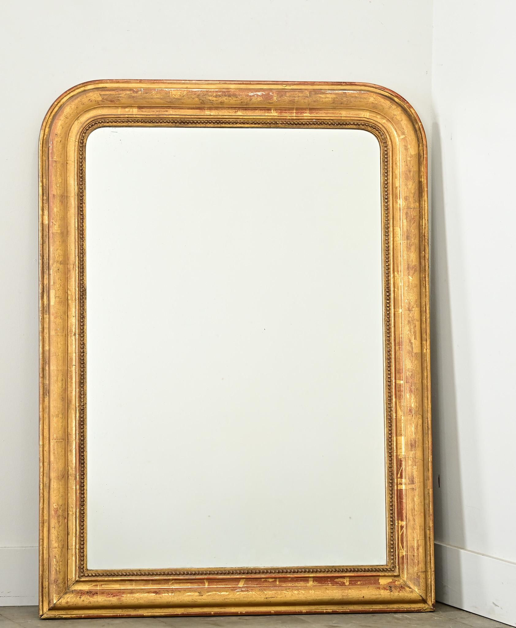 Un beau miroir doré du 19ème siècle en France. Les fortes proportions du cadre en arc de cercle de style Louis Philippe sont soulignées par de minces moulures de feuillage et de perles autour de la plaque de miroir d'origine. De délicates rousseurs