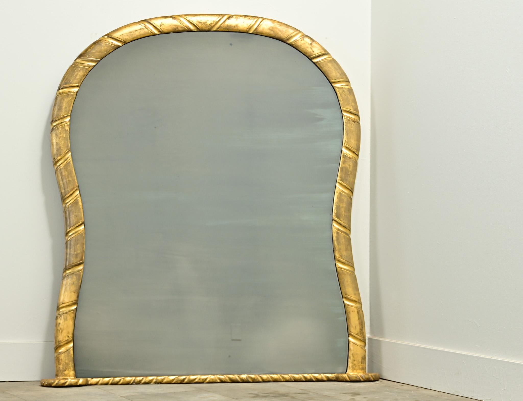 A carved French gold gilt mantle mirror from the 1800’s. The original mirror plate is surrounded by a carved hourglass shaped gold gilt frame. Be sure to view the detailed images to see the current condition.