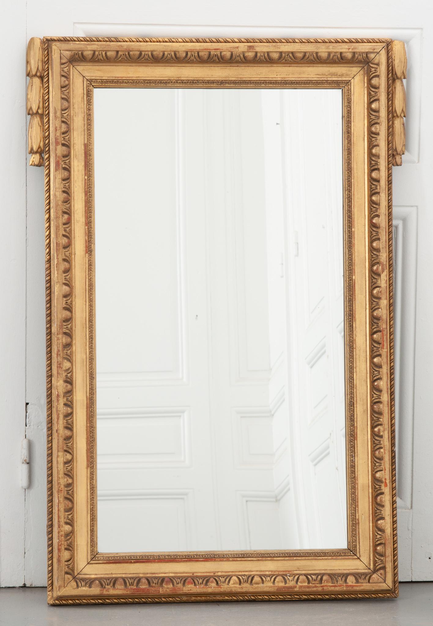 This 19th century French mirror is framed with a fabulously carved gold gilt frame and features a new mirror plate. Layers of decorative carving surround the mirror; a twisted cord on the exterior, egg and dart on the interior, and floral swags on