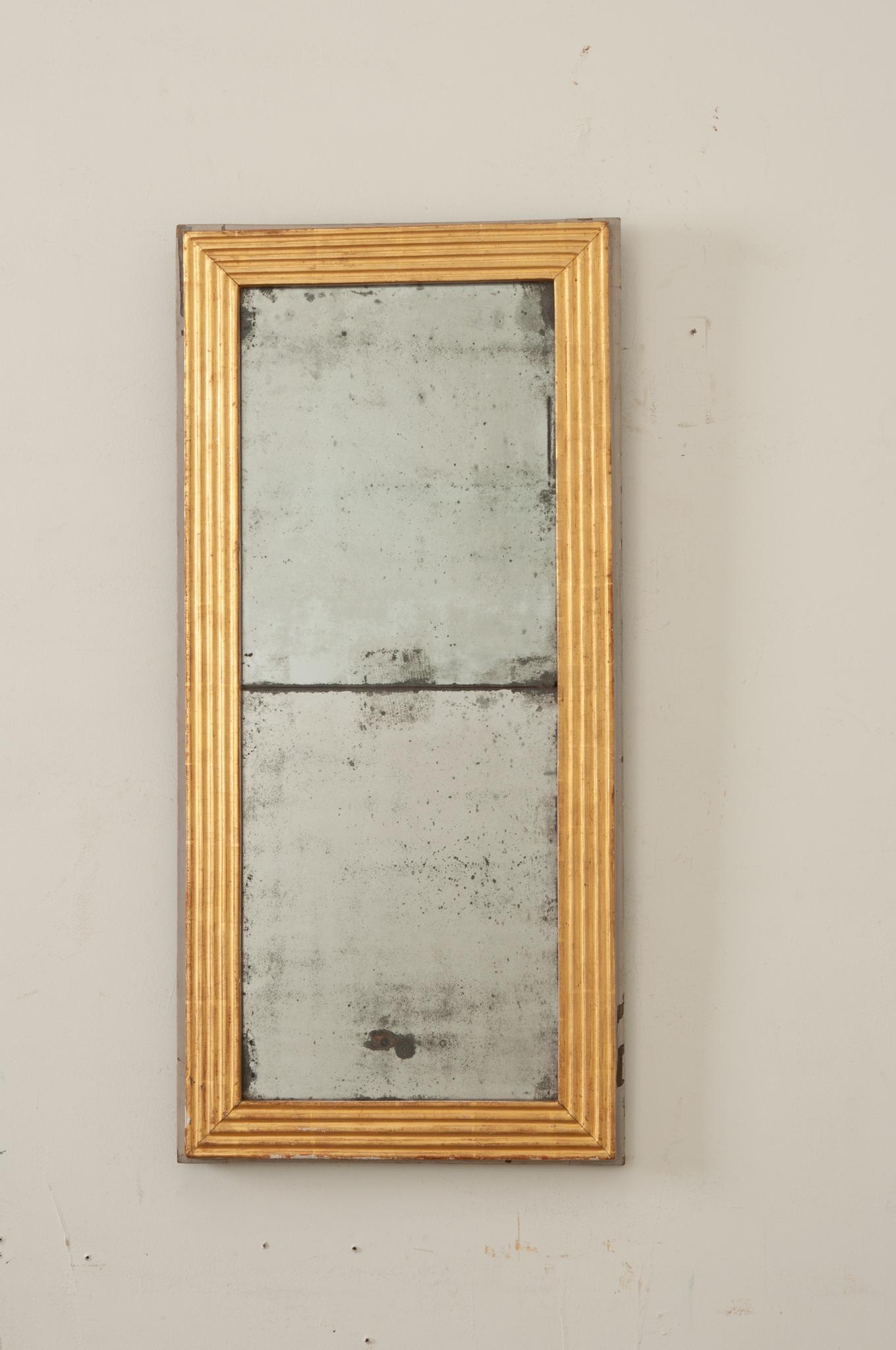 French 19th Century gold gilt mirror with its original glass. The hand-carved wood frame is painted a lustrous gold gilt and is edged in a linear design that creates a beautiful, simple, timeless look.  This mirror is truly stunning, as the heavy