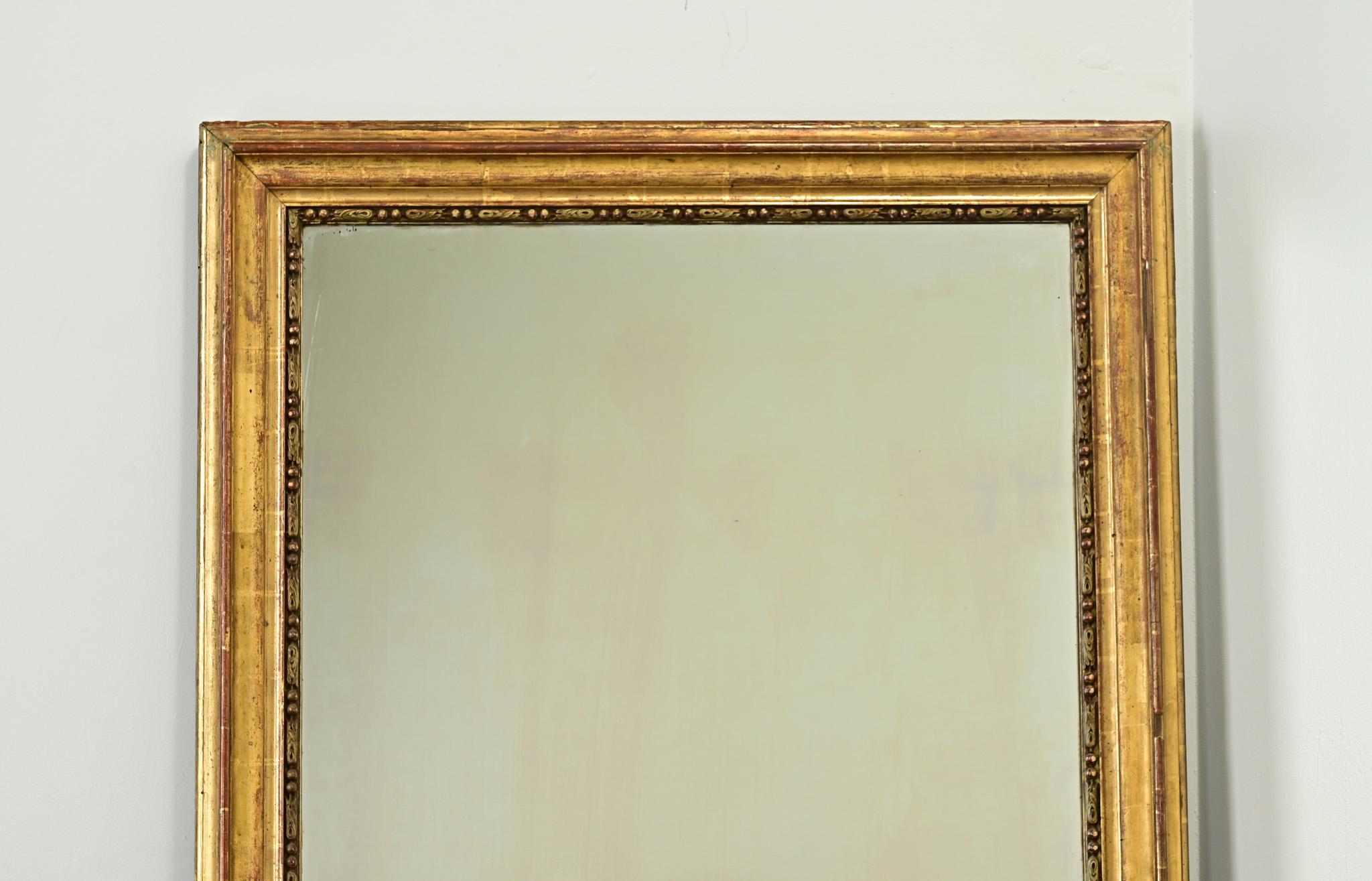 Miroir français doré du 19ème siècle. Le cadre moulé simple a sa finition dorée d'origine, révélant le bole rougeâtre en dessous. La plaque de miroir plus récente présente un vieillissement minimal. N'oubliez pas de regarder les images détaillées de