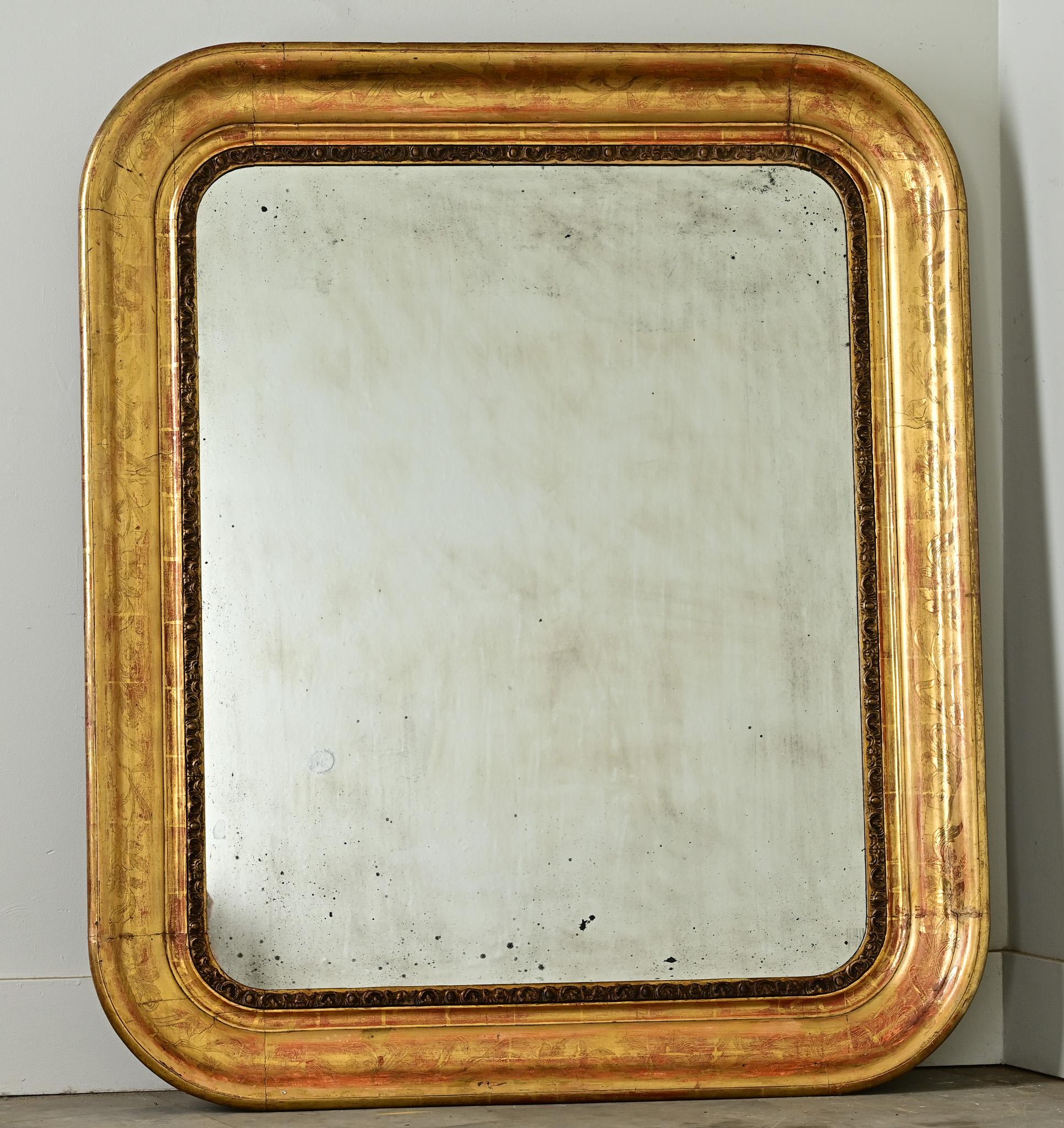 Ce miroir distinct, datant du milieu ou de la fin des années 1800 en France, témoigne d'une grande expression artistique dans chaque détail. Le cadre large et arrondi est méticuleusement sculpté de fleurs exotiques fantastiques ou stylisées, le bole