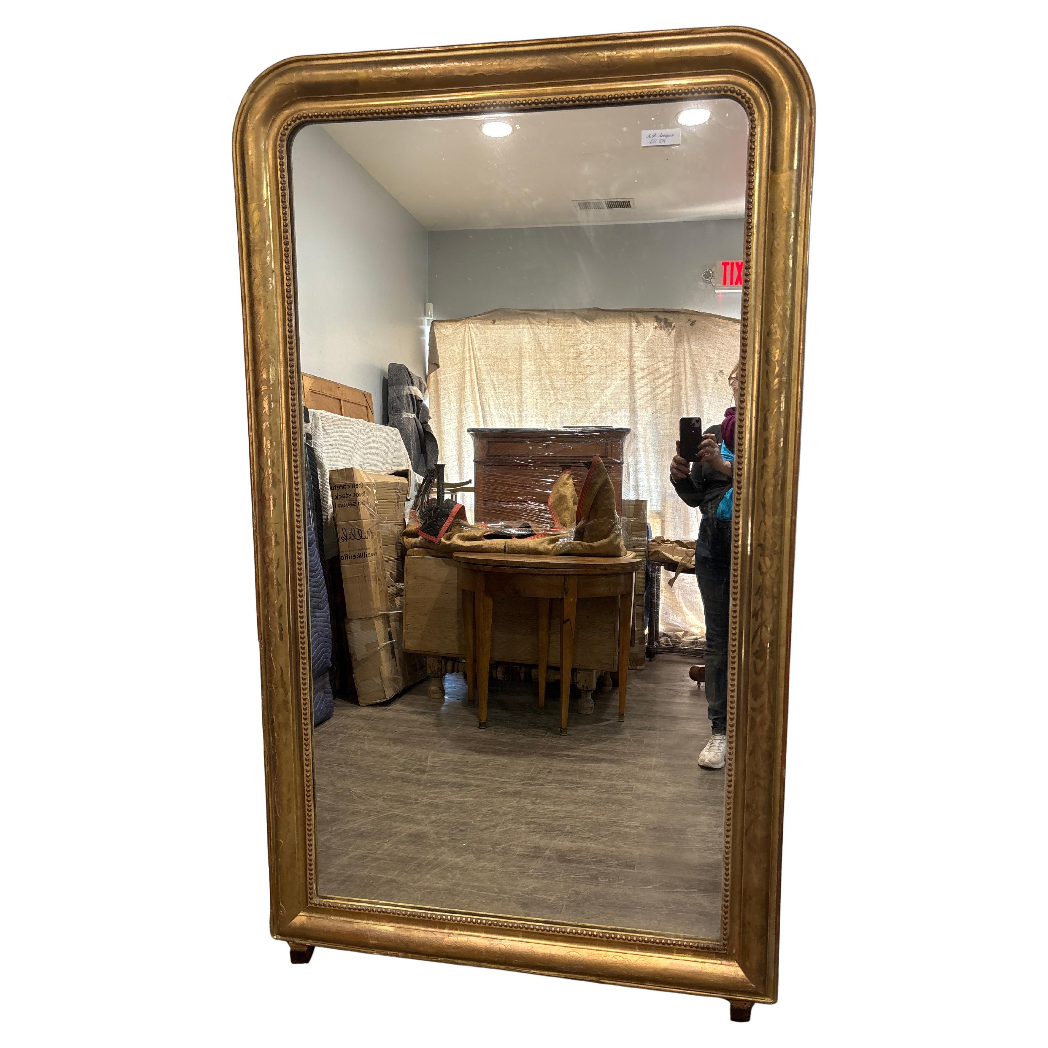 Questo meraviglioso specchio alto Louis Philippe è realizzato in legno, ricoperto da un sottile strato di gesso e di colore rosso. Le foglie d'oro sono applicate su di esso. Lo specchio in vetro è un vetro al mercurio ed è in buone condizioni.