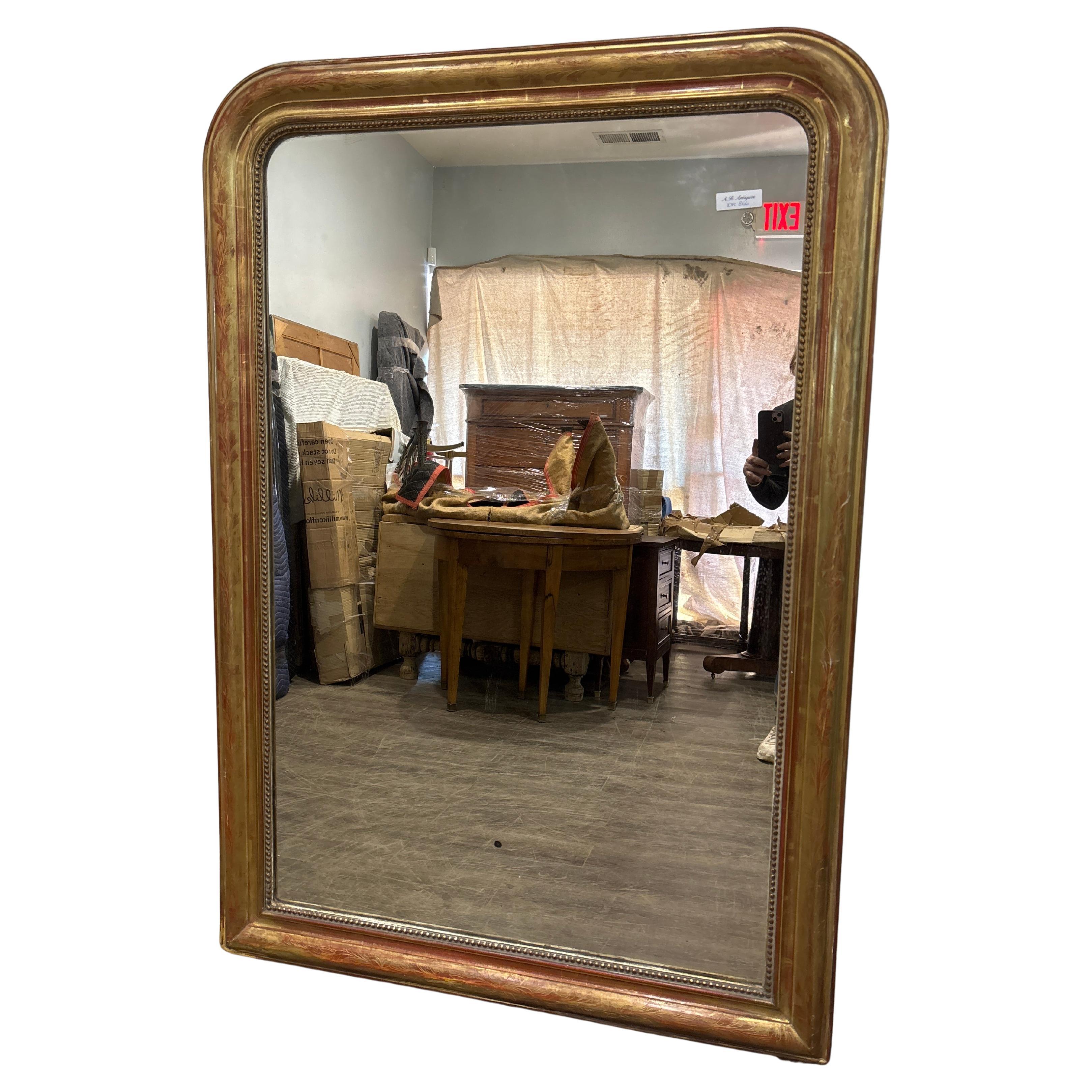 Questo meraviglioso specchio alto Louis Philippe è realizzato in legno, ricoperto da un sottile strato di gesso e di colore rosso. Le foglie d'oro sono applicate su di esso. Lo specchio in vetro è un vetro al mercurio ed è in buone condizioni.