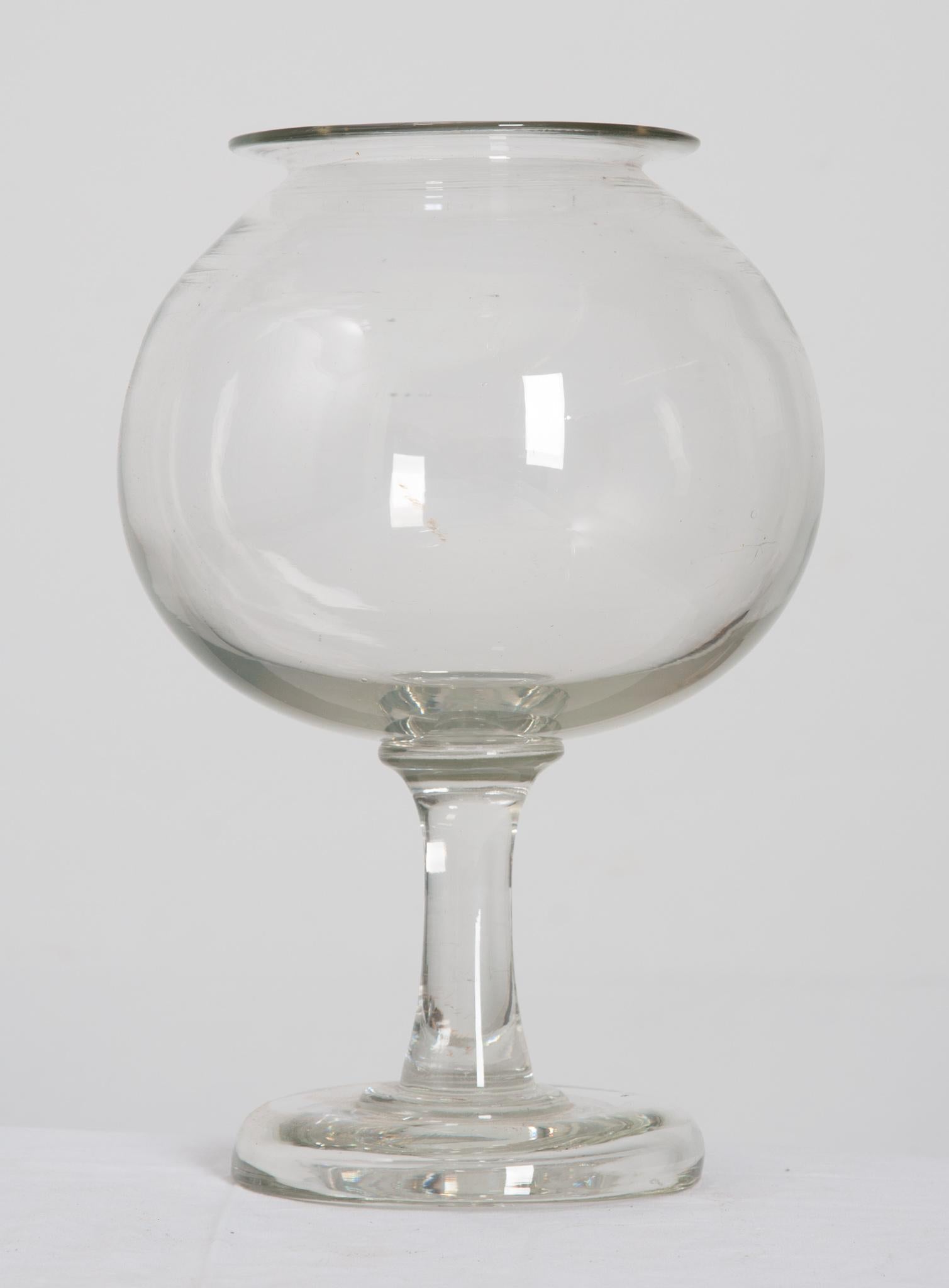 This clear glass fishbowl is the perfect antique for any home! Made from thick glass the lipped bowl is elevated by a sturdy pedestal of glass. Goldfish bowls were incredibly popular in Victorian era England. Finding one in this condition, without