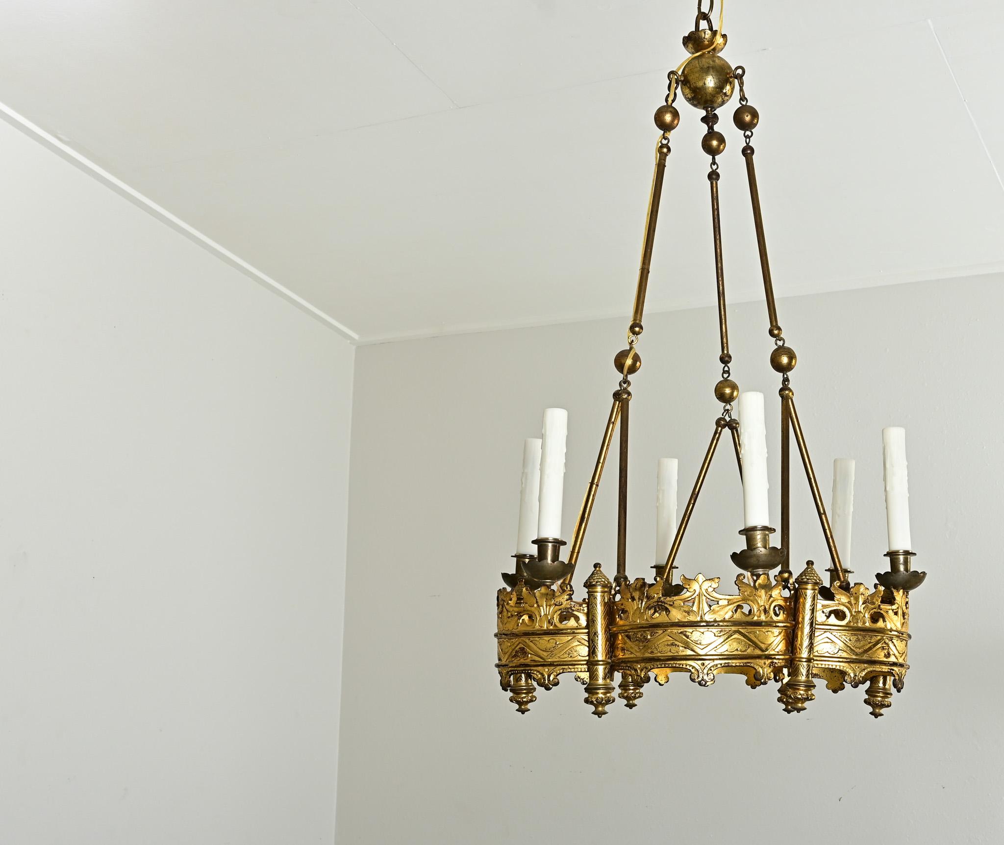 Uno splendido lampadario a 6 luci in ottone in stile gotico proveniente dalla Francia del XIX secolo. L'apparecchio, dallo stile drammatico, ha una base a forma di multi-foglio da cui si estendono le sei luci. La base è legata a un baldacchino