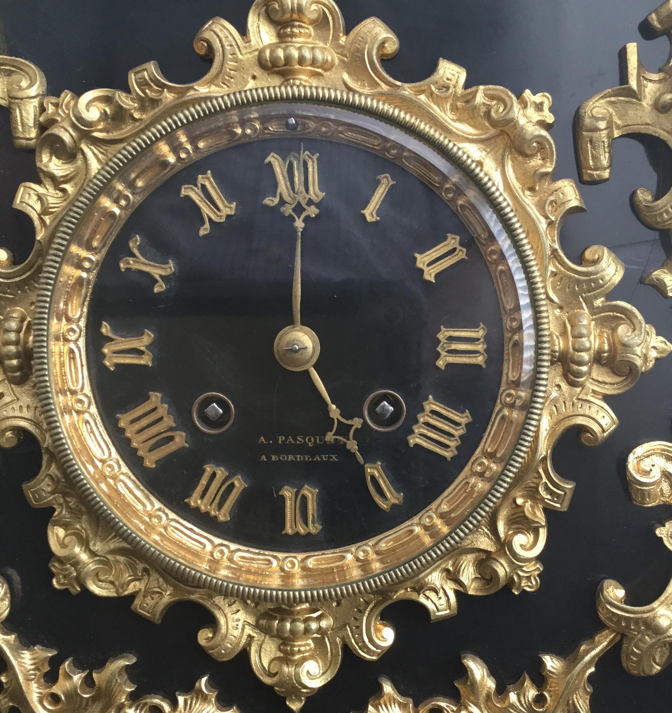 A French early 19th century Gothic style black slate and bronze mantel or library clock of outstanding quality with gilt highlights, the case profusely decorated with swirling leaf and berry patterns, the body highlighted with male and female busts