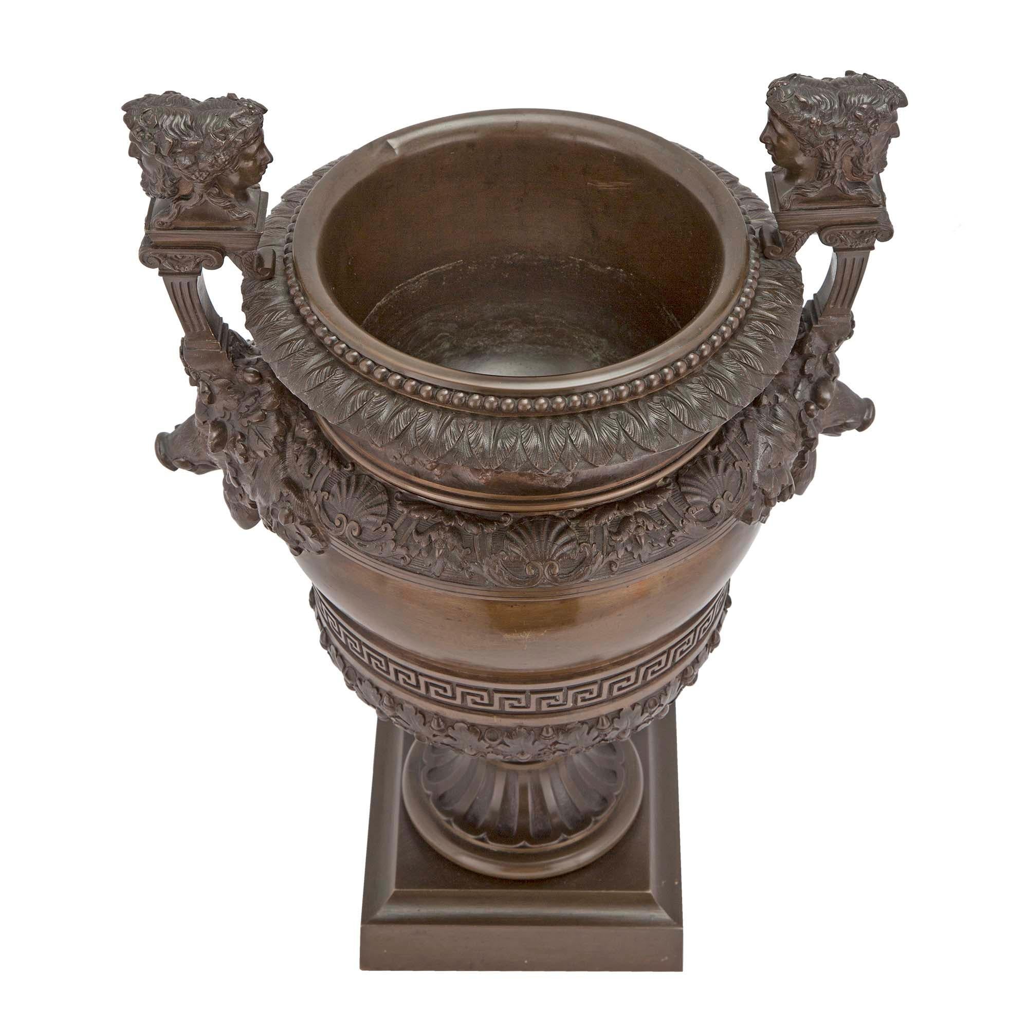 A handsome French 19th century Grand Tour period patinated bronze urn. The urn is raised by a mottled square base below the fluted socle pedestal. The body is decorated with richly chased foliate patterns and a striking Greek key design. At each