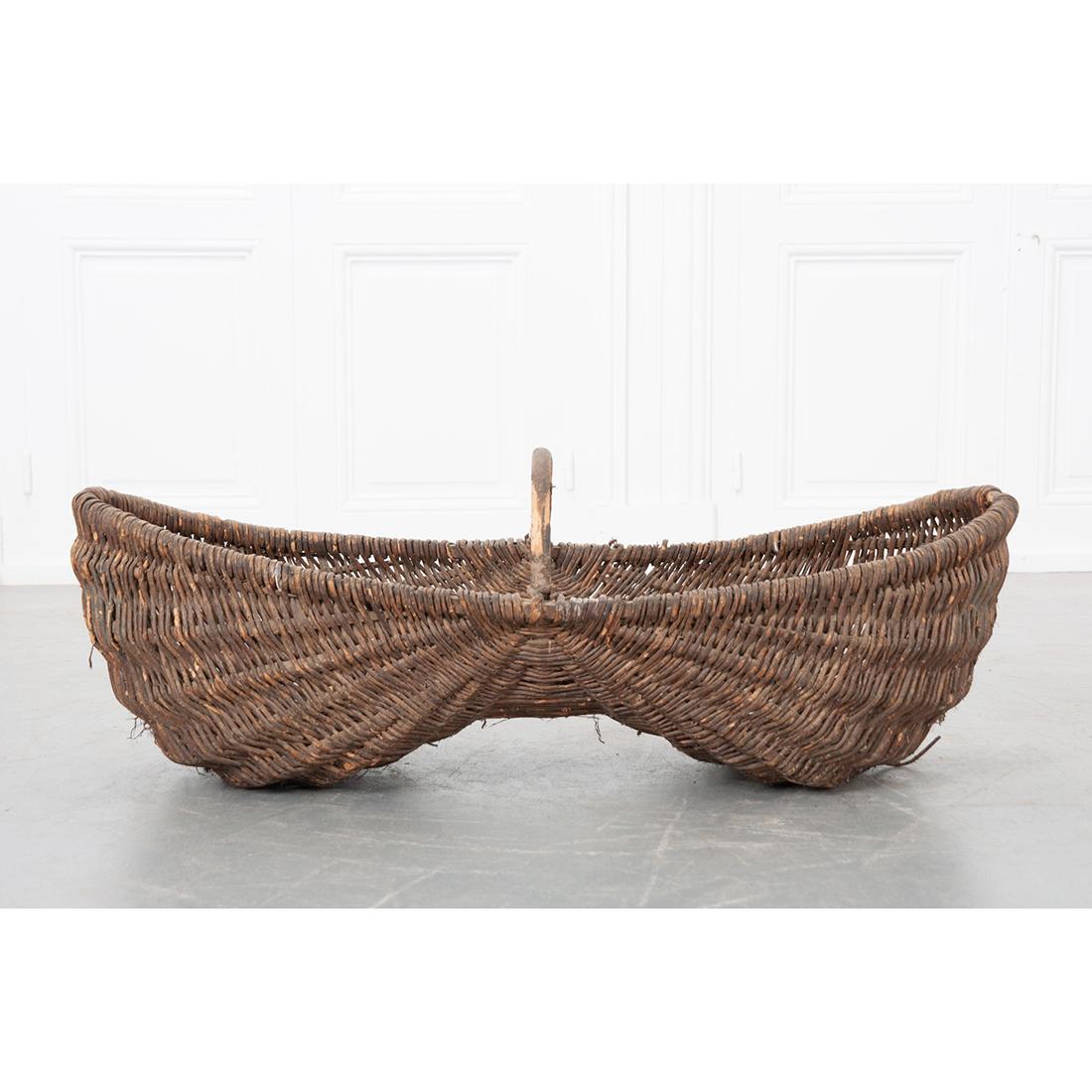 Decorate with this antique, grape harvest, gathering basket. Created in the Burgundy region of France, circa 1890. This unique basket is made of handwoven wicker is a capsule shape and features a wooden frame with arched handle across the top. This