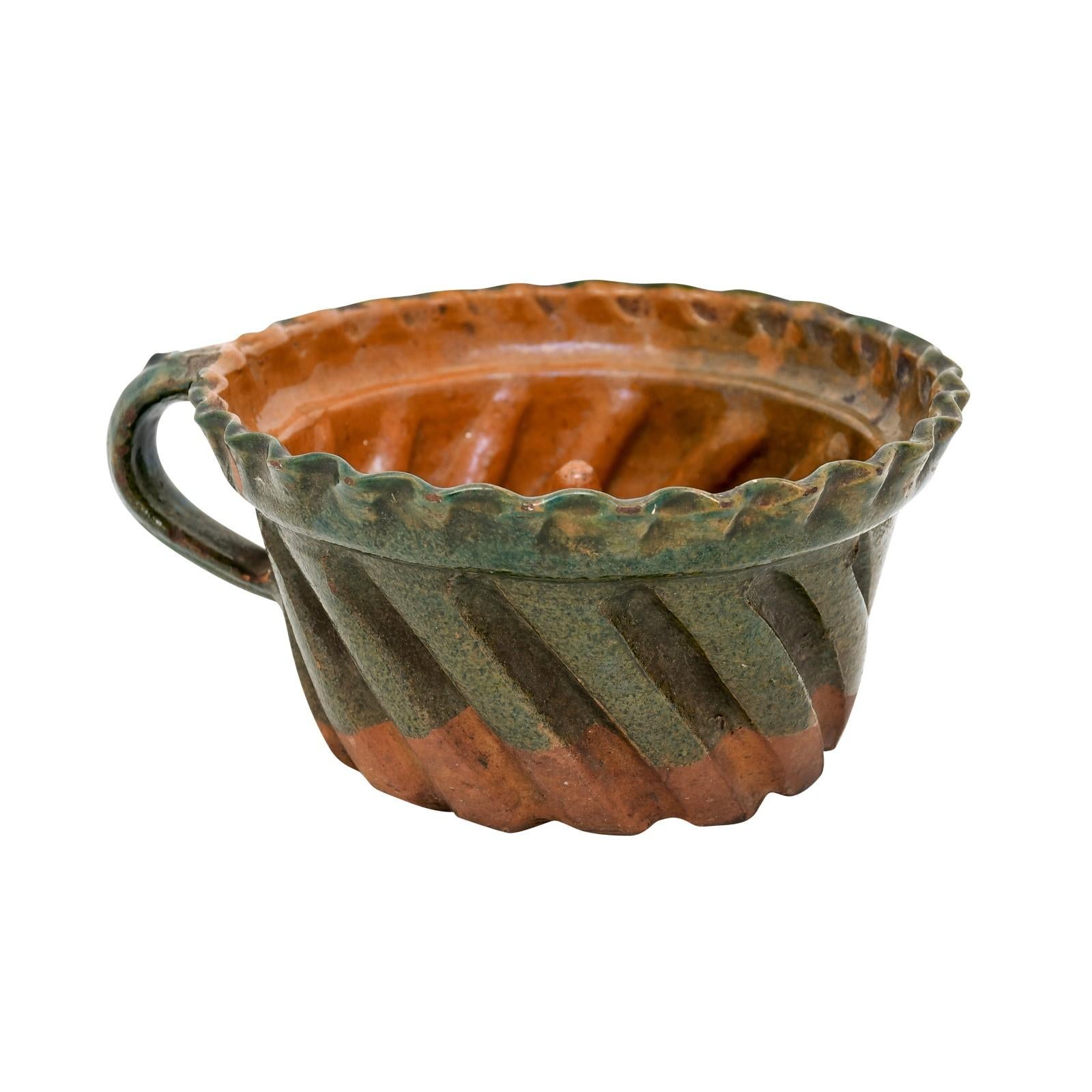 A rustic French pottery cake mold from the 19th century with green glaze. Delight in the antique charm of this 19th century French pottery cake mold. With its rustic allure and charmingly antiquated design, this piece encapsulates the beauty of